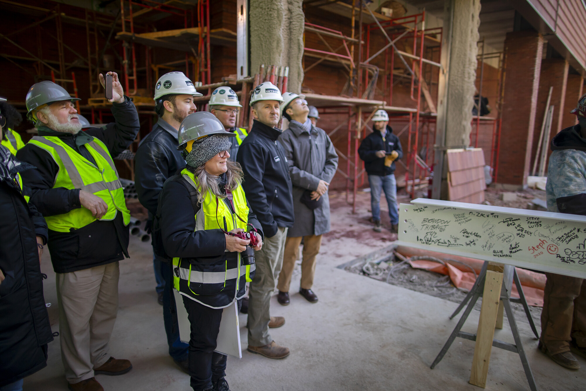 A group of people involved with the New College House&nbsp;West construction, including the architect on the far left, stand before the final beam before it is lifted in place.&nbsp;