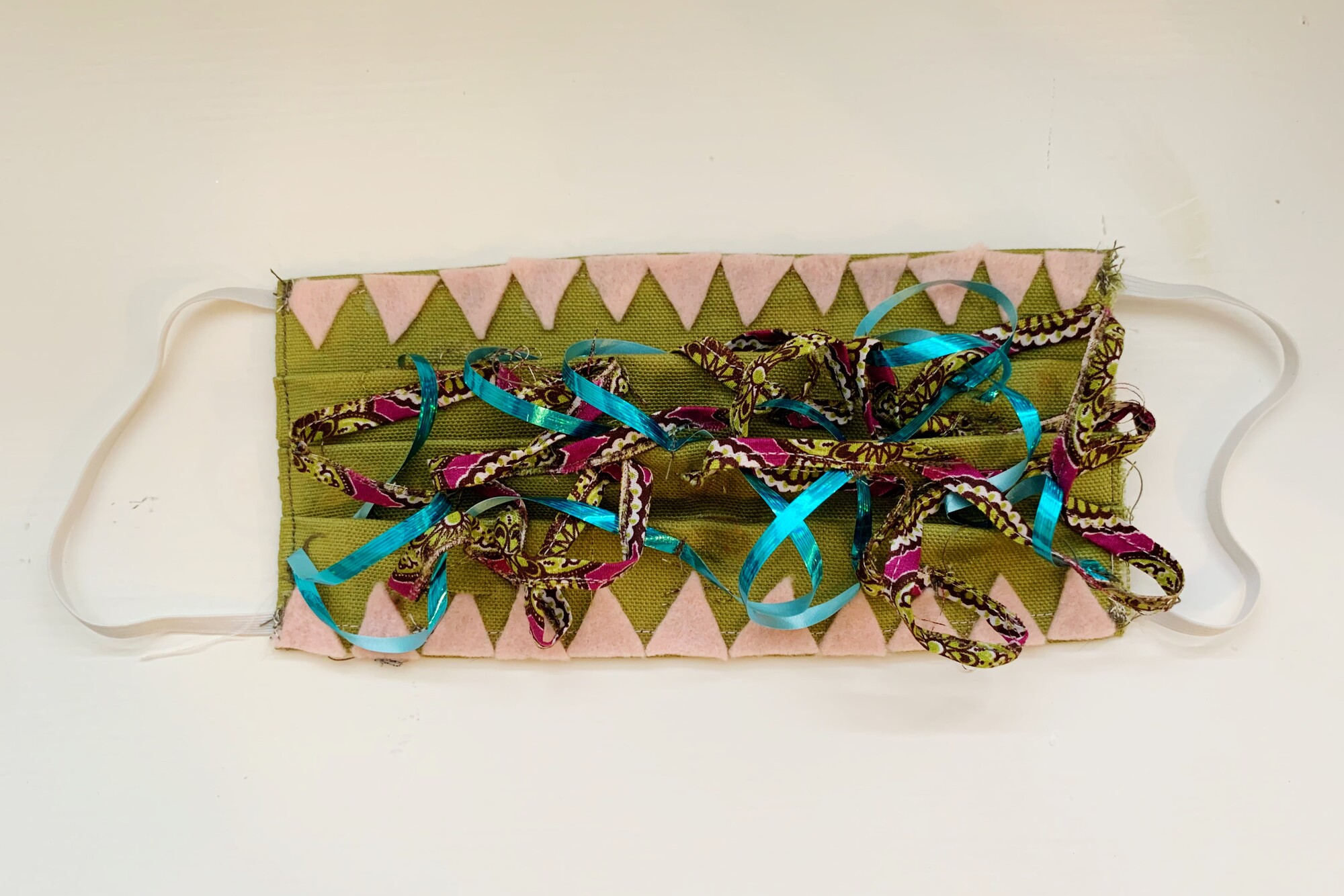 a mask with many ribbons in the middle and jagged teeth on the edges