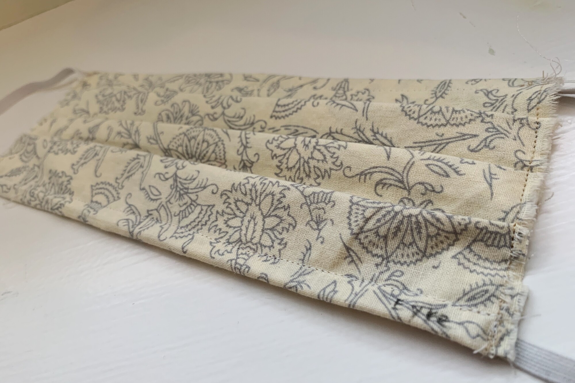 A mask made of muslin fabric with a floral design in grey