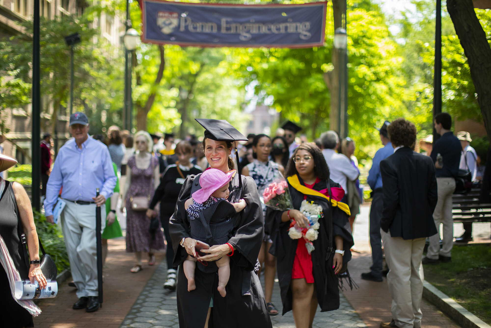 graduate carrying baby down locust walk