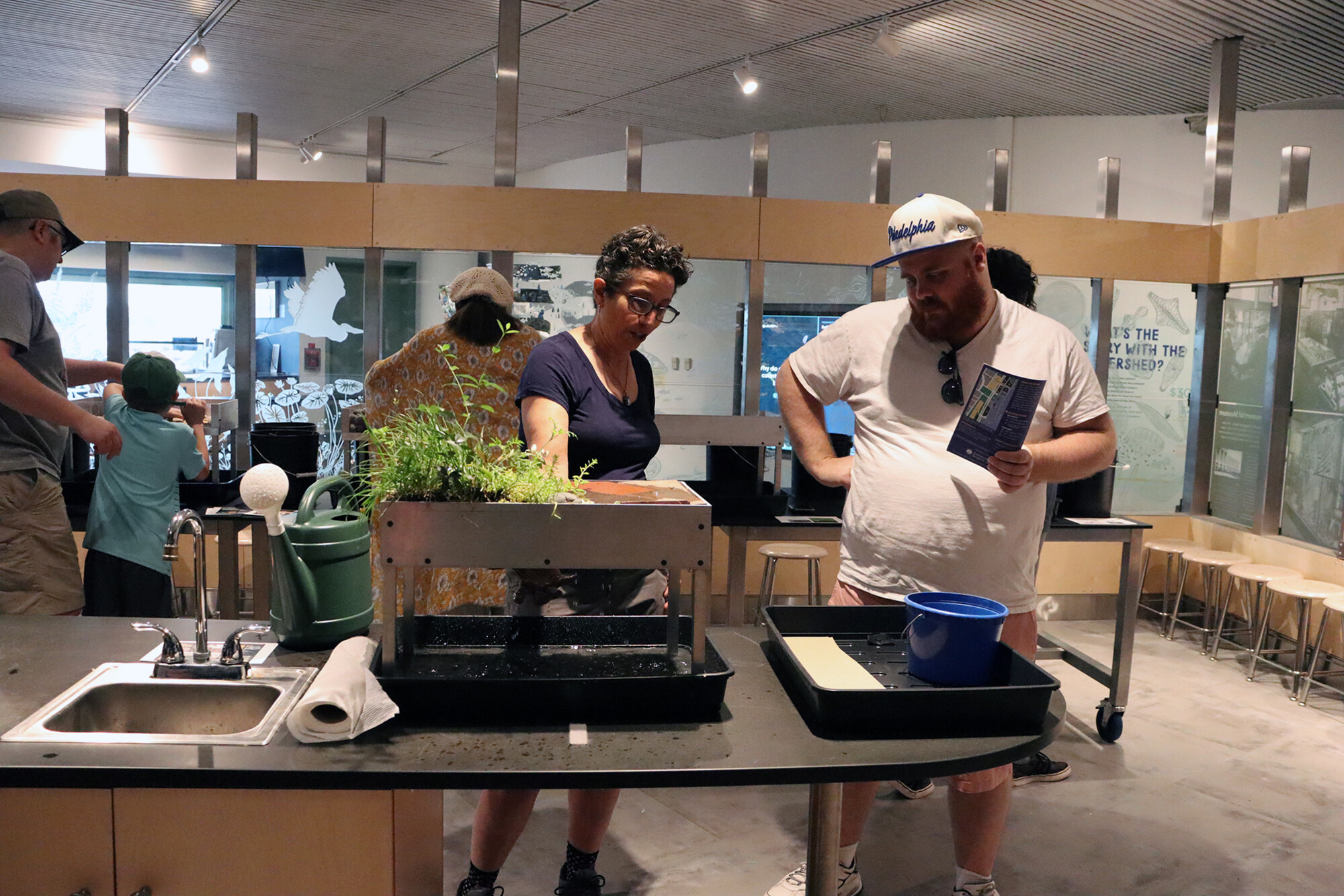 People in a lab, two are looking at plant matter.