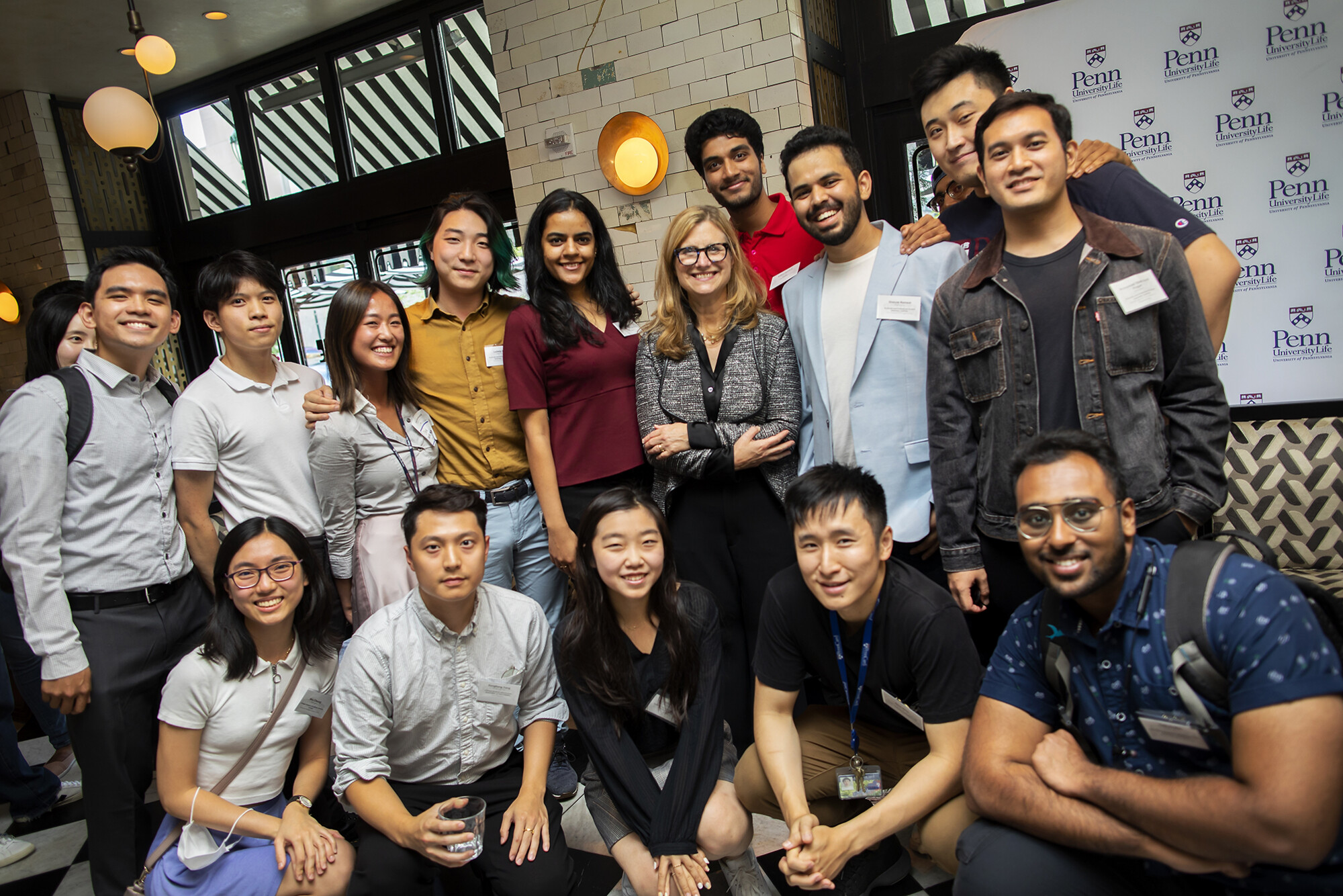 Graduate students smile for a photo with Liz Magill in the center