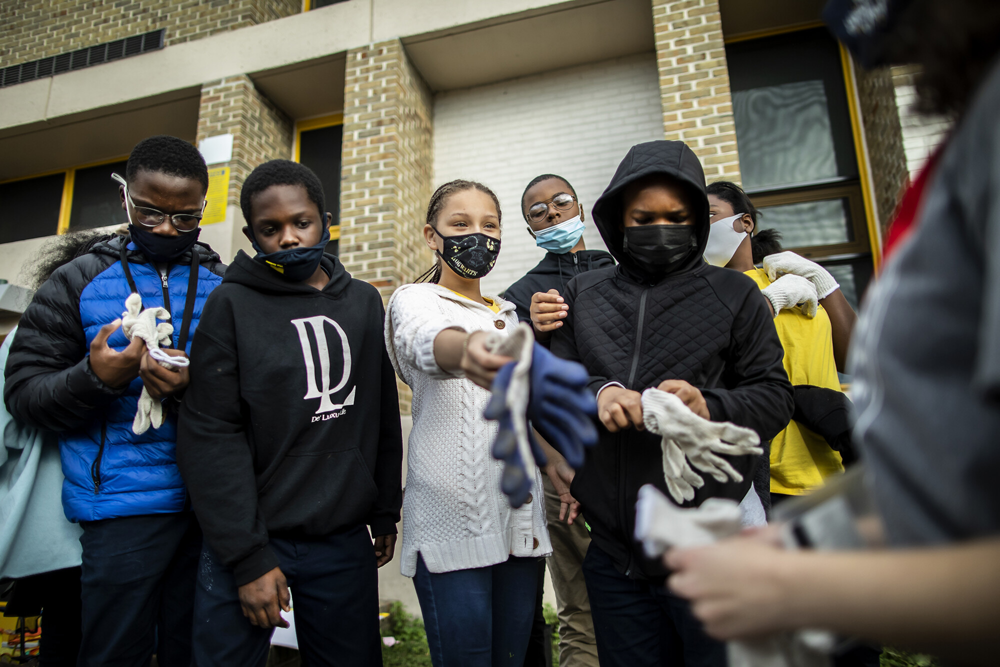 A group of Hamilton Elementary students outside the school taking off gardening gloves.