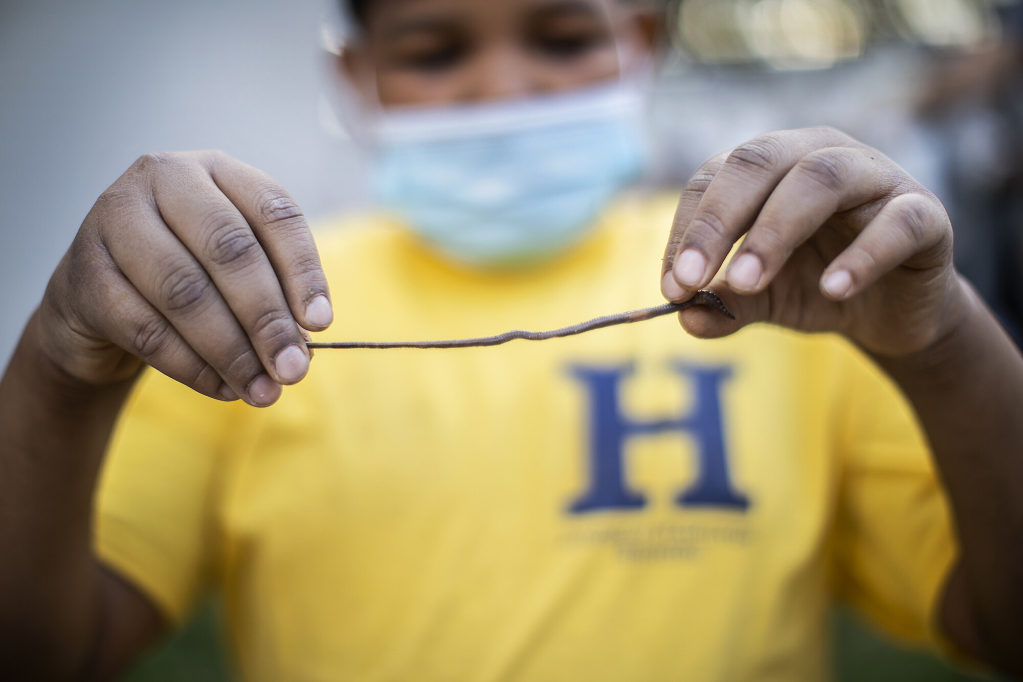 A Hamilton student holds up a worm during the tree planting event.
