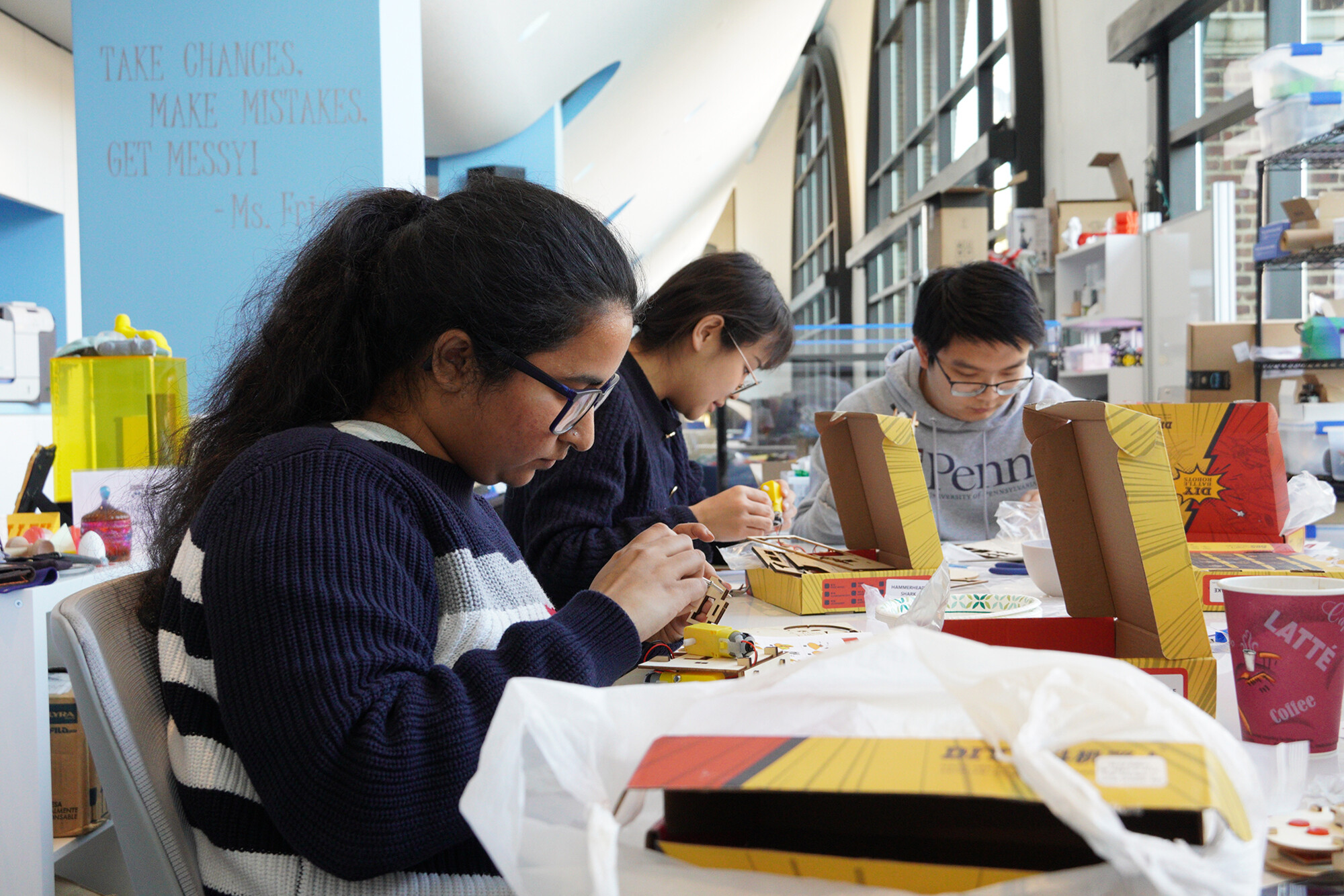 Three students working on a DIY robotics kit at the Education Commons.