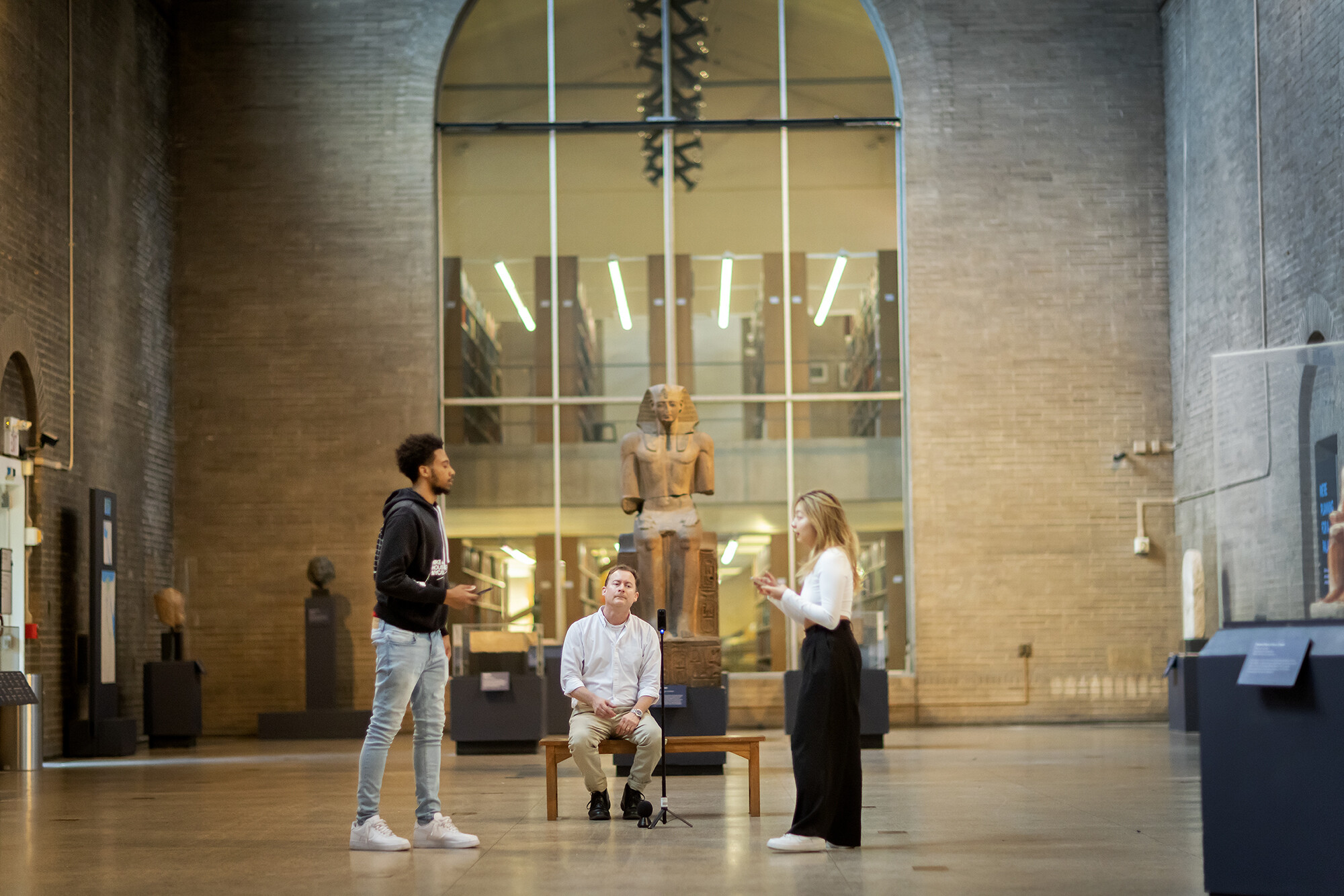 Joseph Wegner and two students in a large atrium in the Penn Museum.