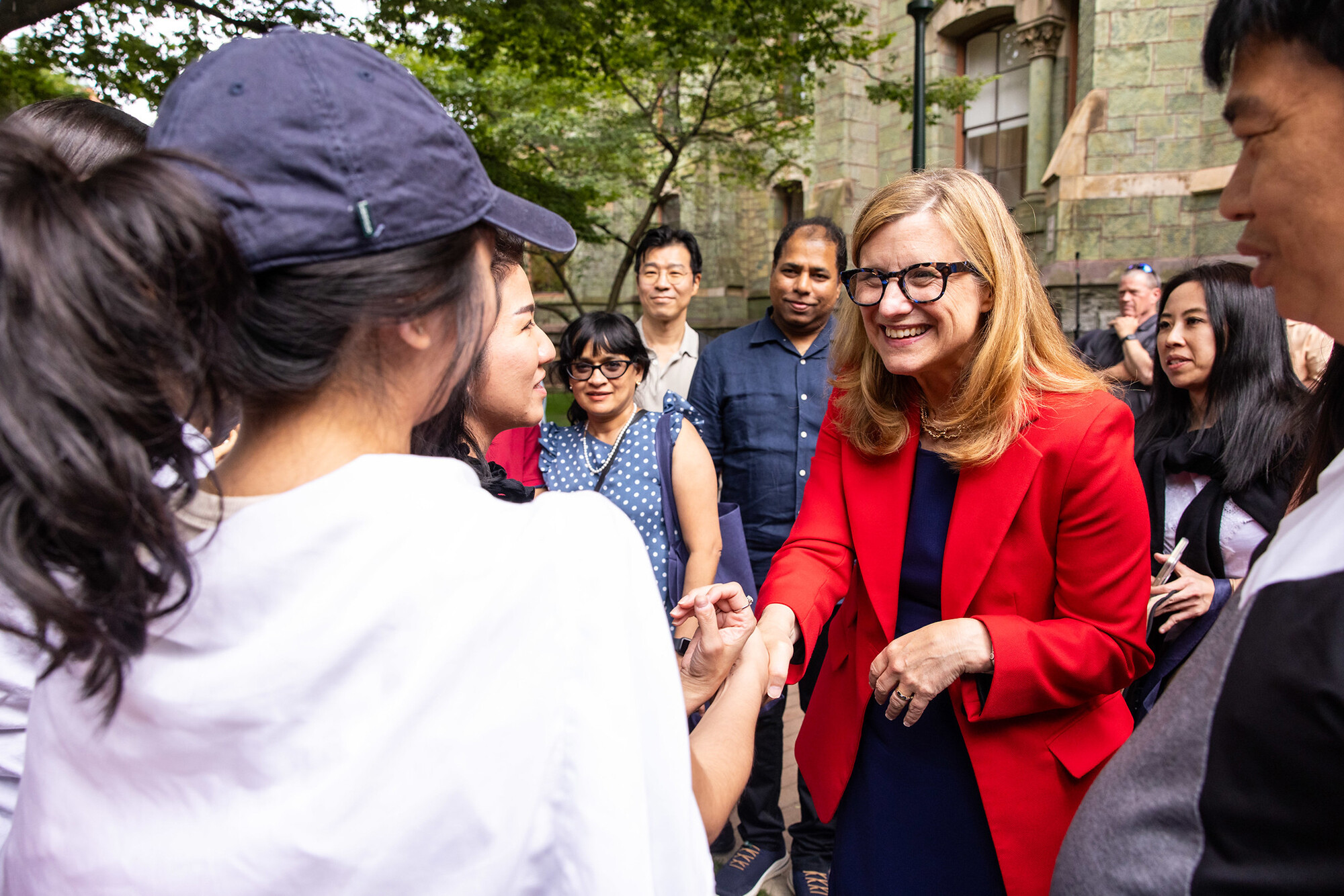Penn President Liz Magill shakes the hand of a new student and their family in front of College Hall.