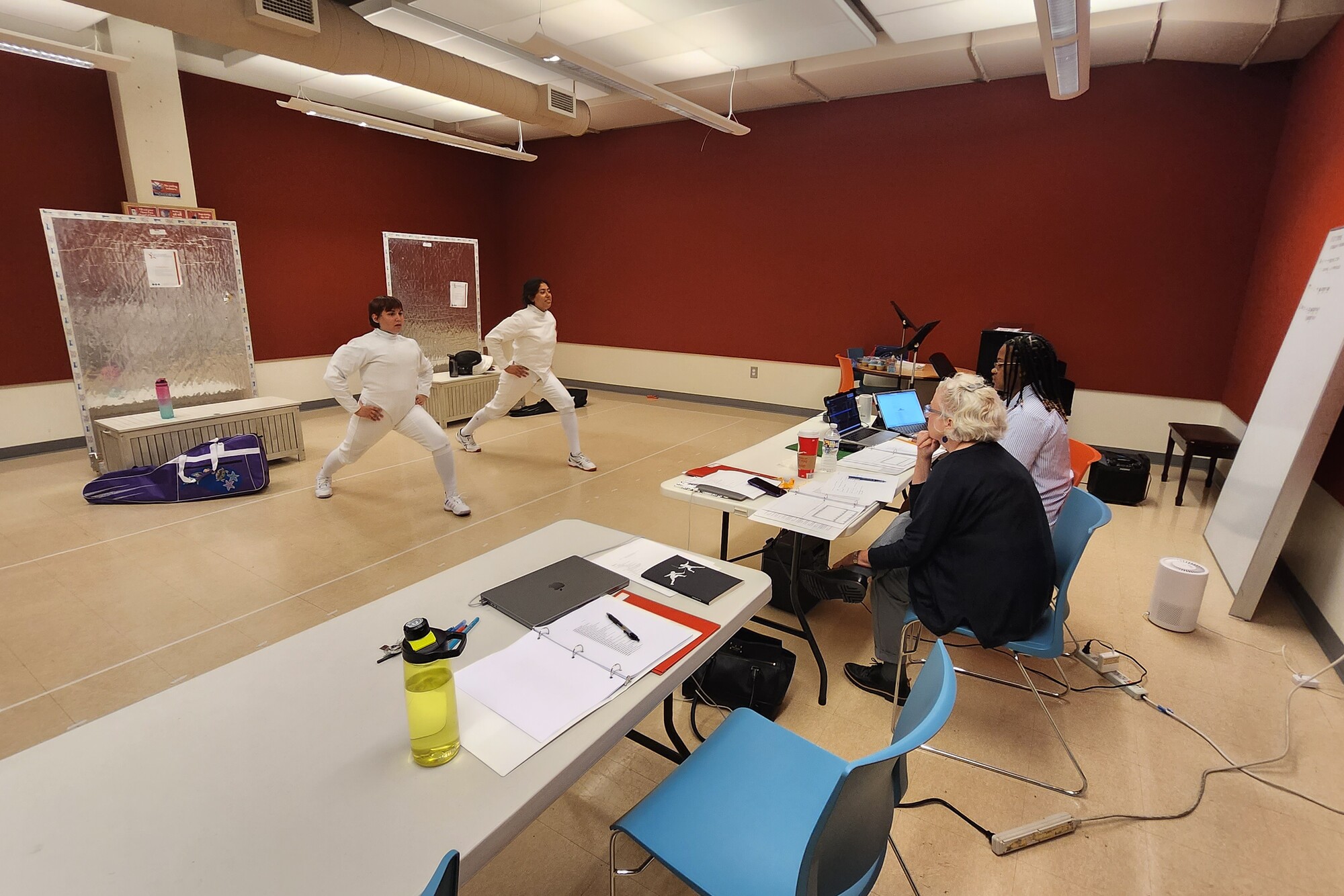 Two actors lunging in front of two seated play directors during play rehearsal.