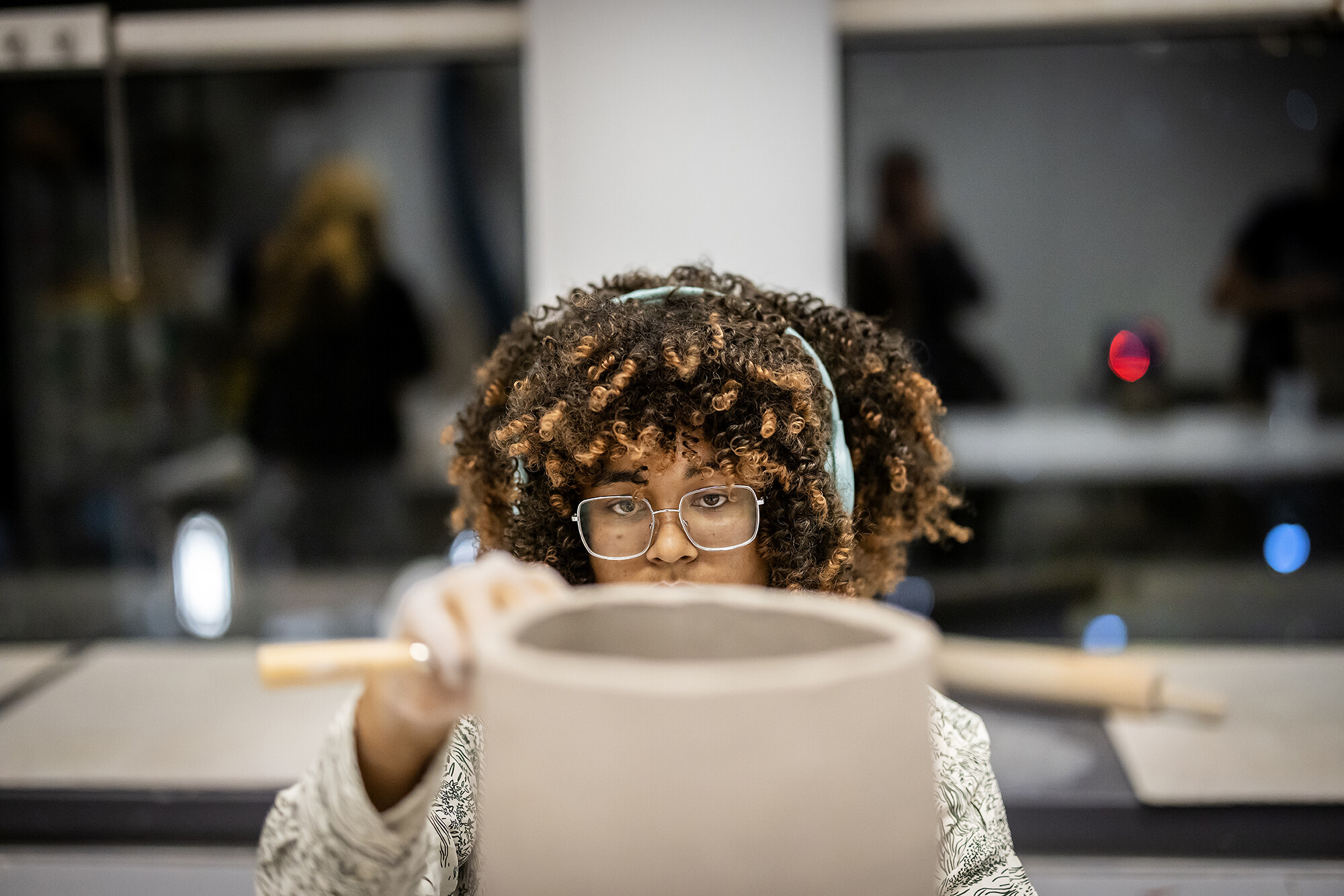 student trimming clay on a piece of pottery