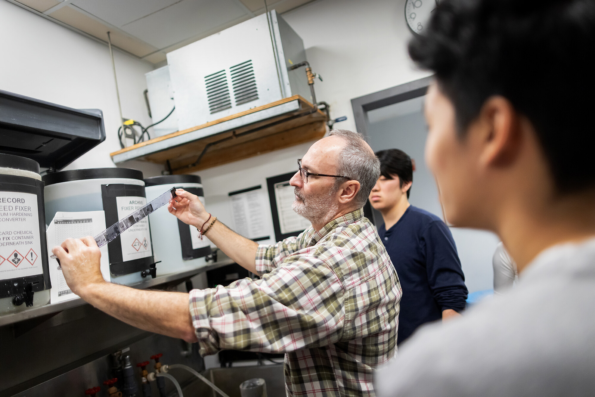 gabe martinez works with students in the darkroom