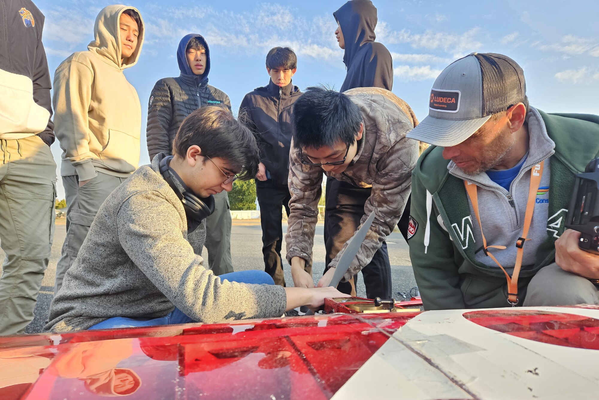 Students and an adviser working outside on the aerial racing plane.