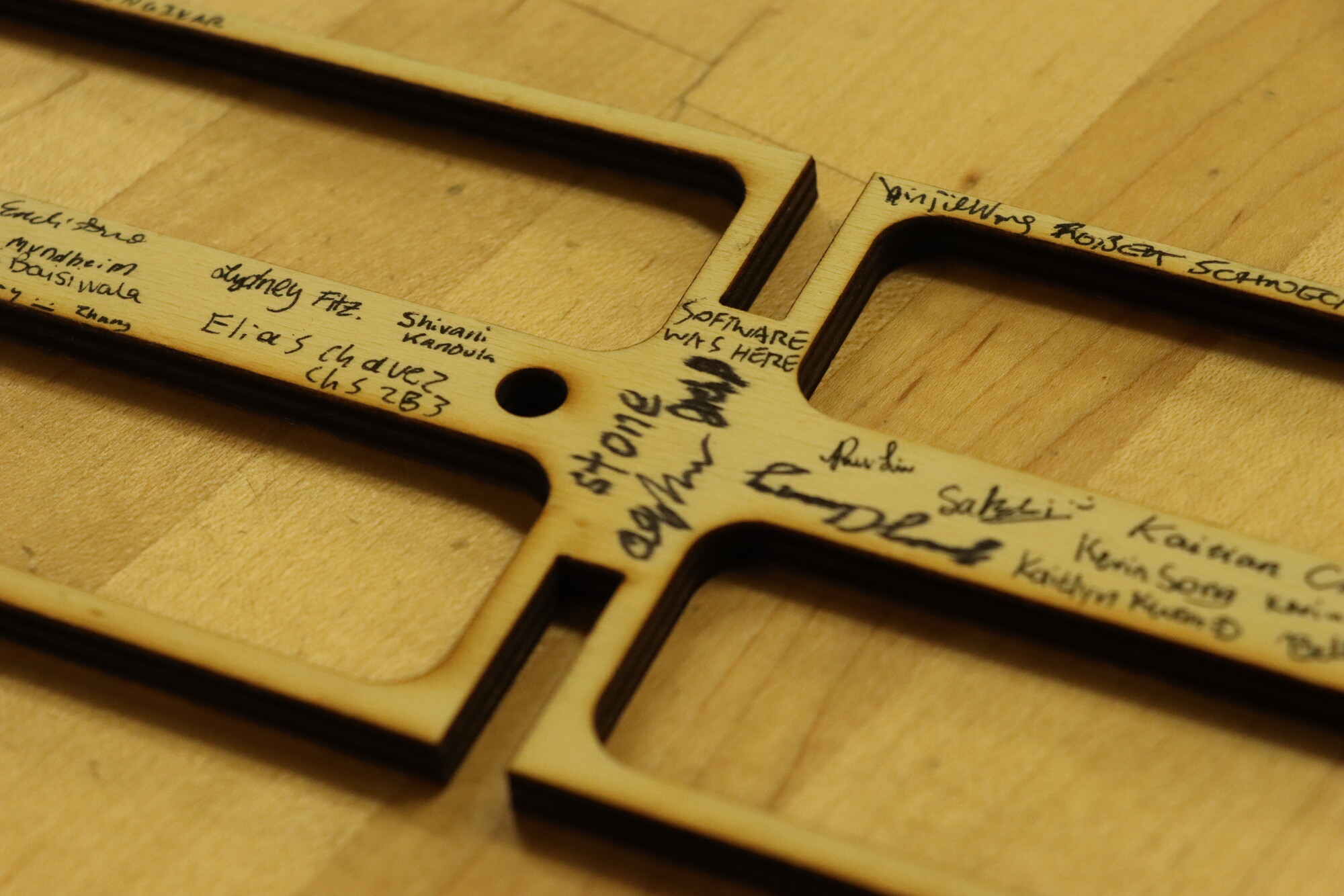 A closeup of a piece of wood that makes up the aerial plane parts with students’ signatures.