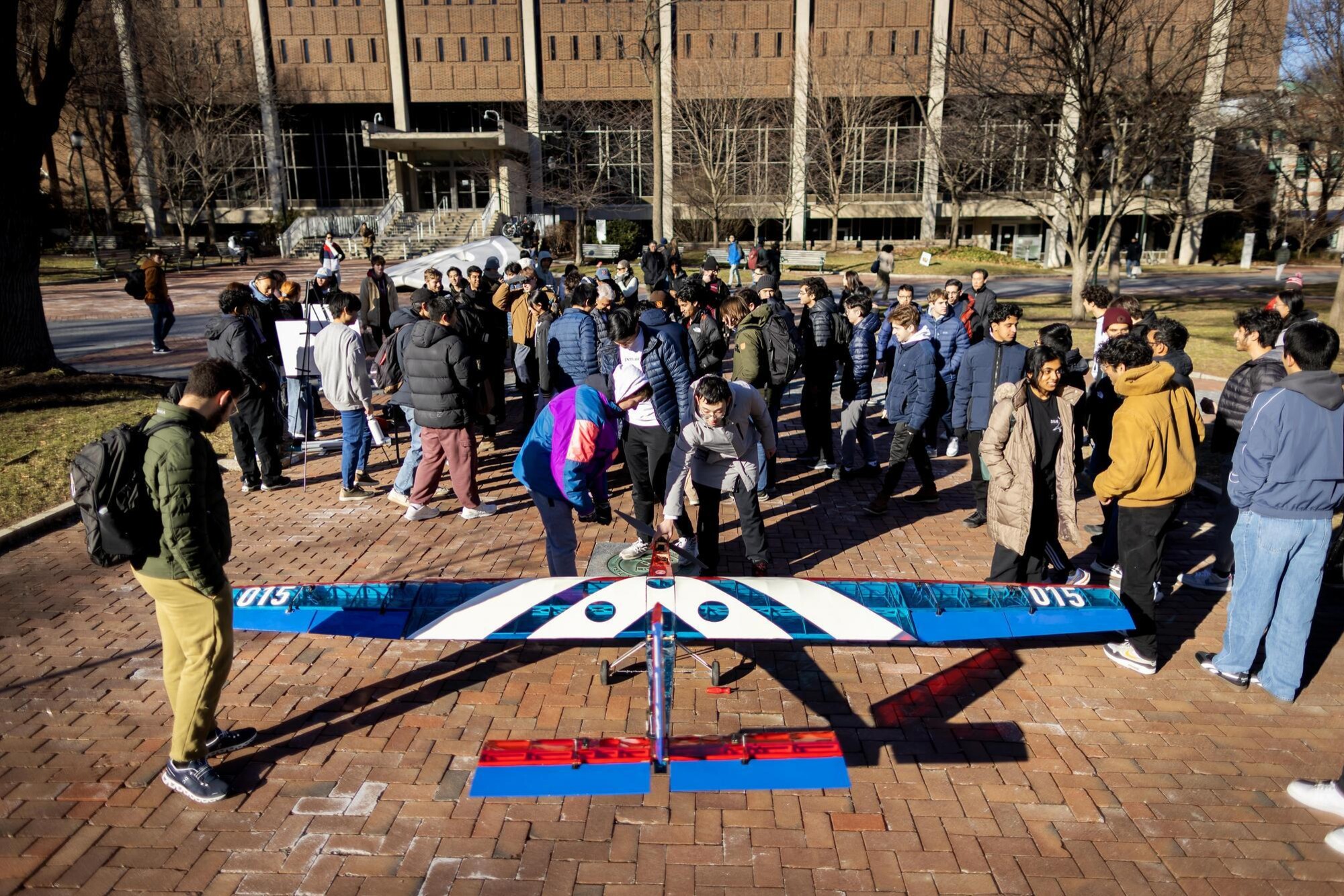 Penn’s aerial drone plane on Locust Walk in front of Van Pelt Library with students.