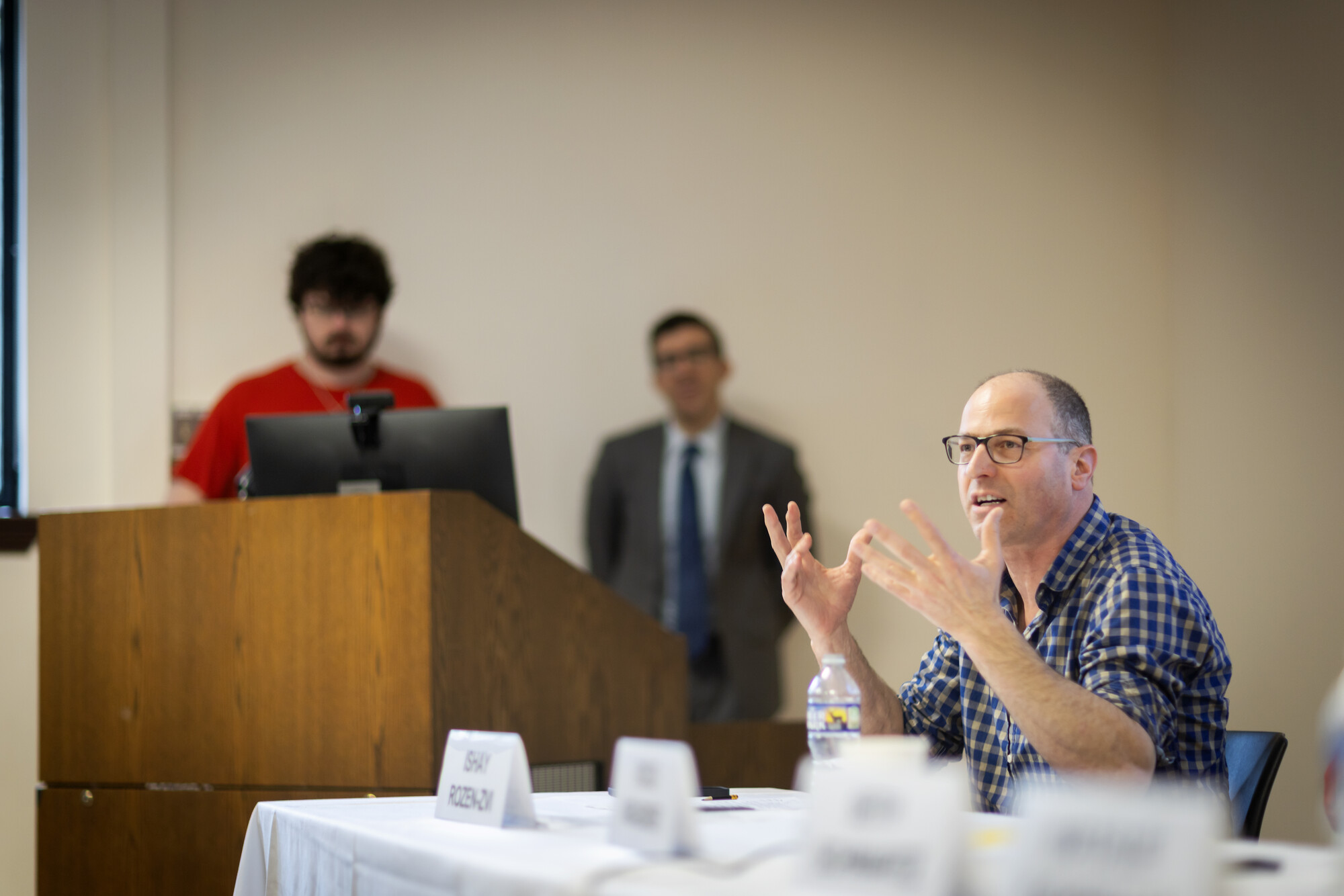 Ishay gestures while seated with a panel.