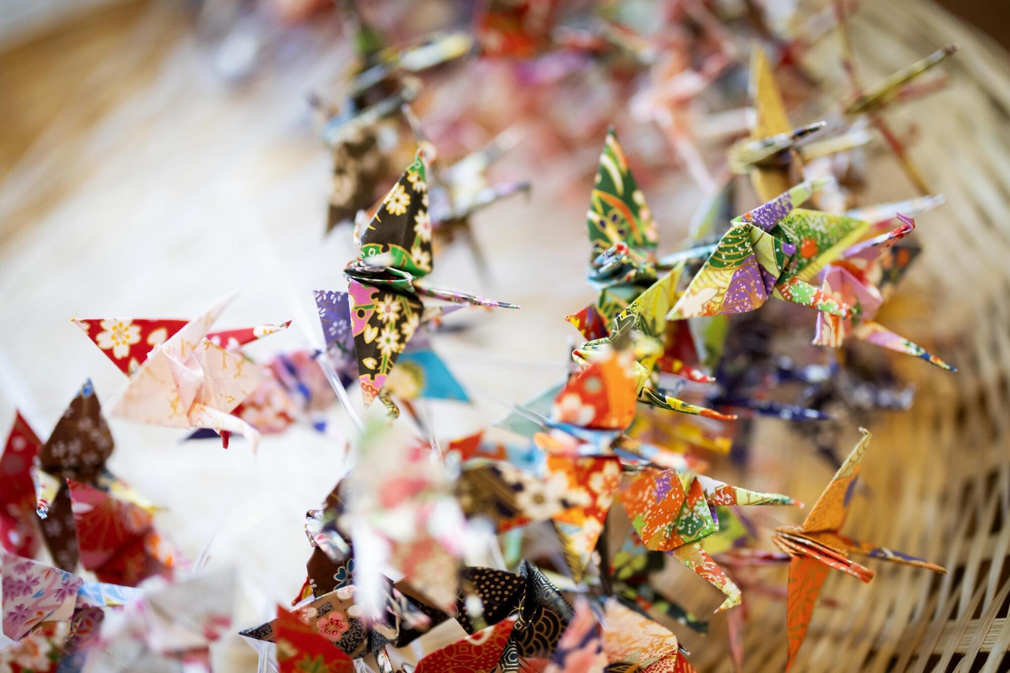 Numerous tiny folded origami cranes in a basket.