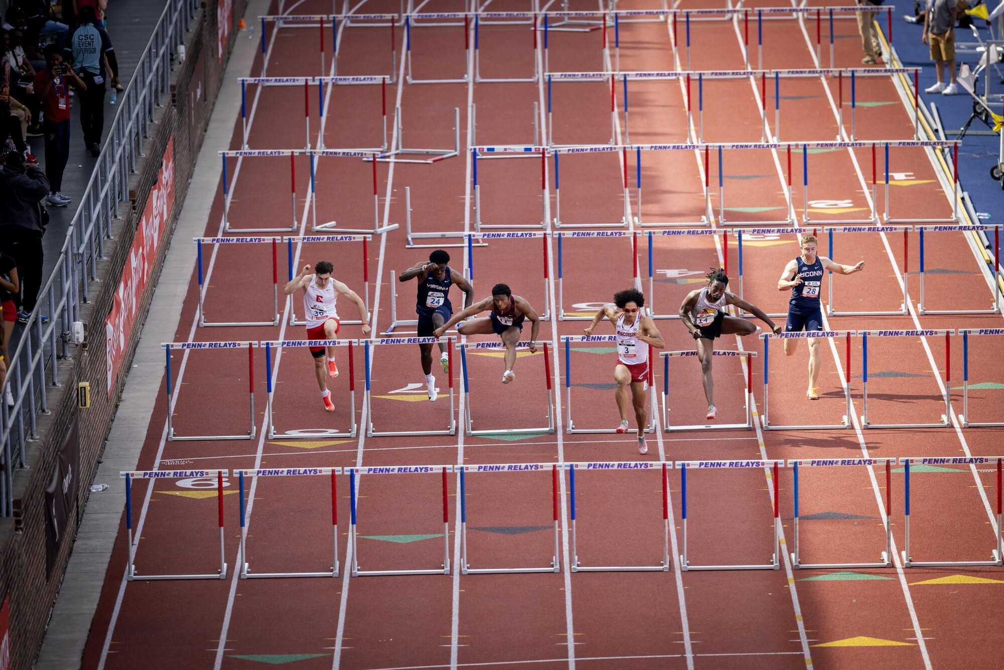 Runners jumping over hurdles at the Penn Relays.