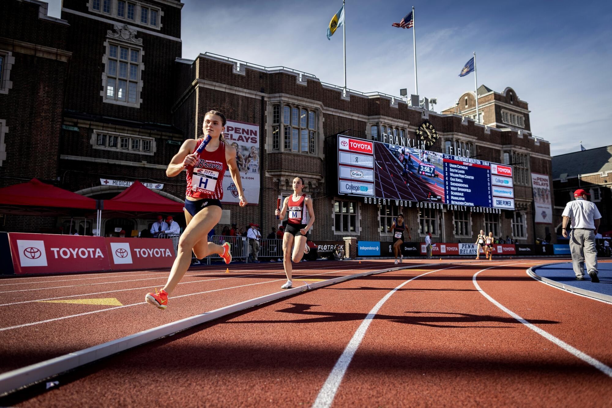 Runners running on the track at Franklin Field during the Penn Relays.