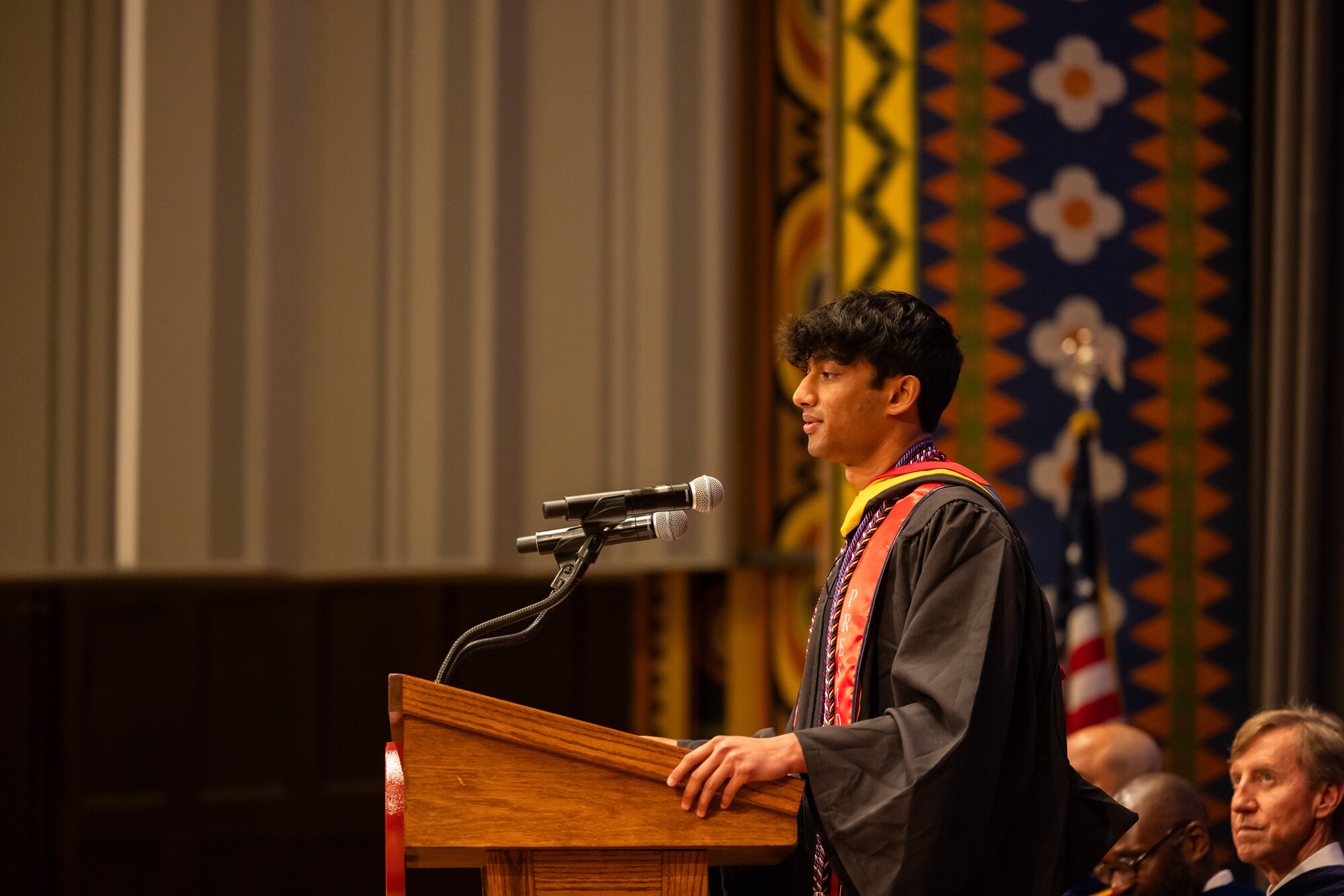 The president of Penn’s Class of 2025 speaking at the podium at the Baccalaureate celebration.
