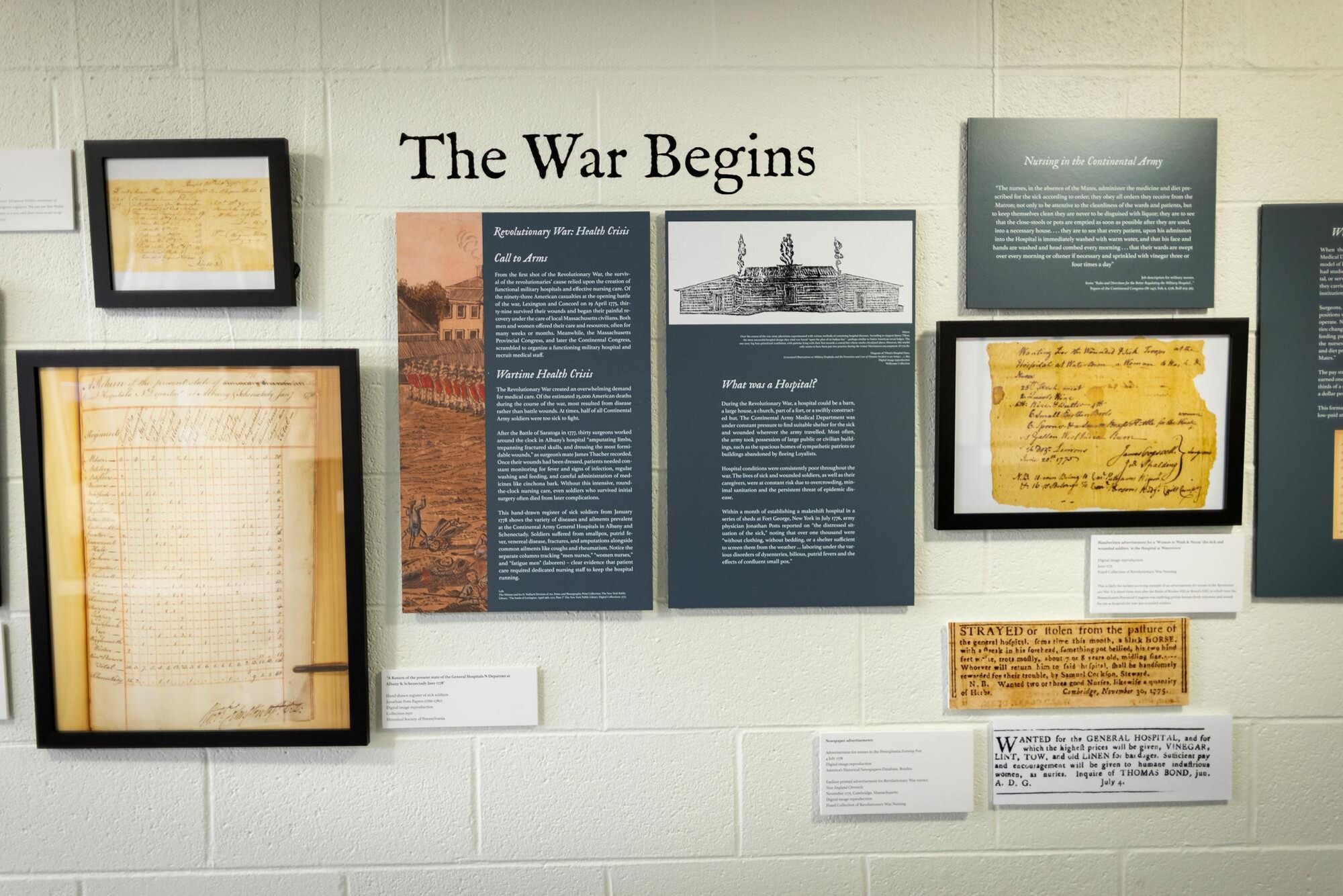 The Revolutionary War nursing history exhibit, “The War Begins” wall of nursing papers and photographs.