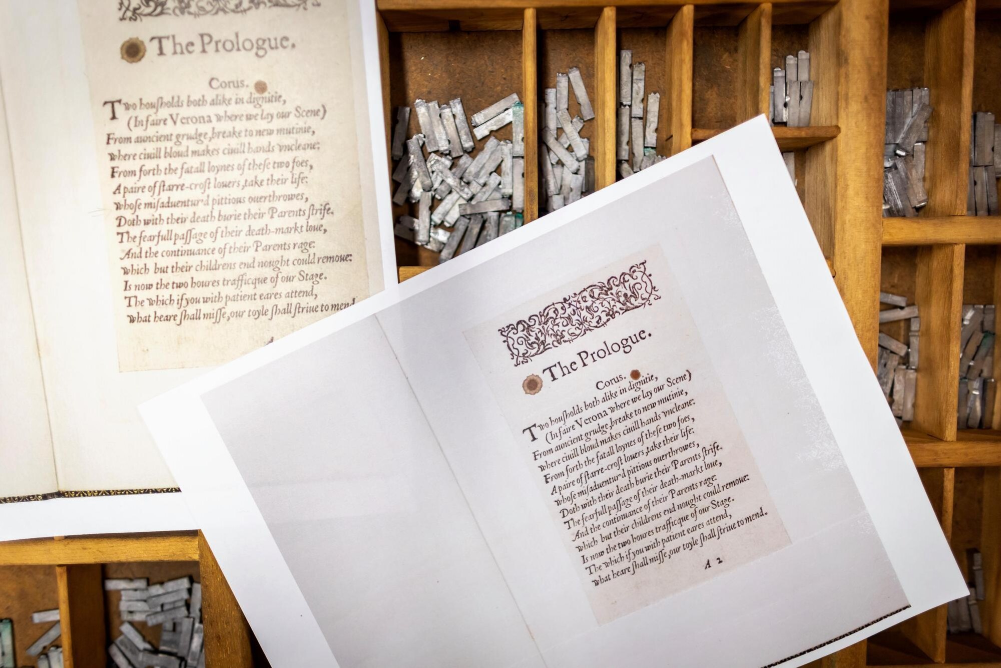 Copies of a historic text on top of a wooden box of letterpress type.