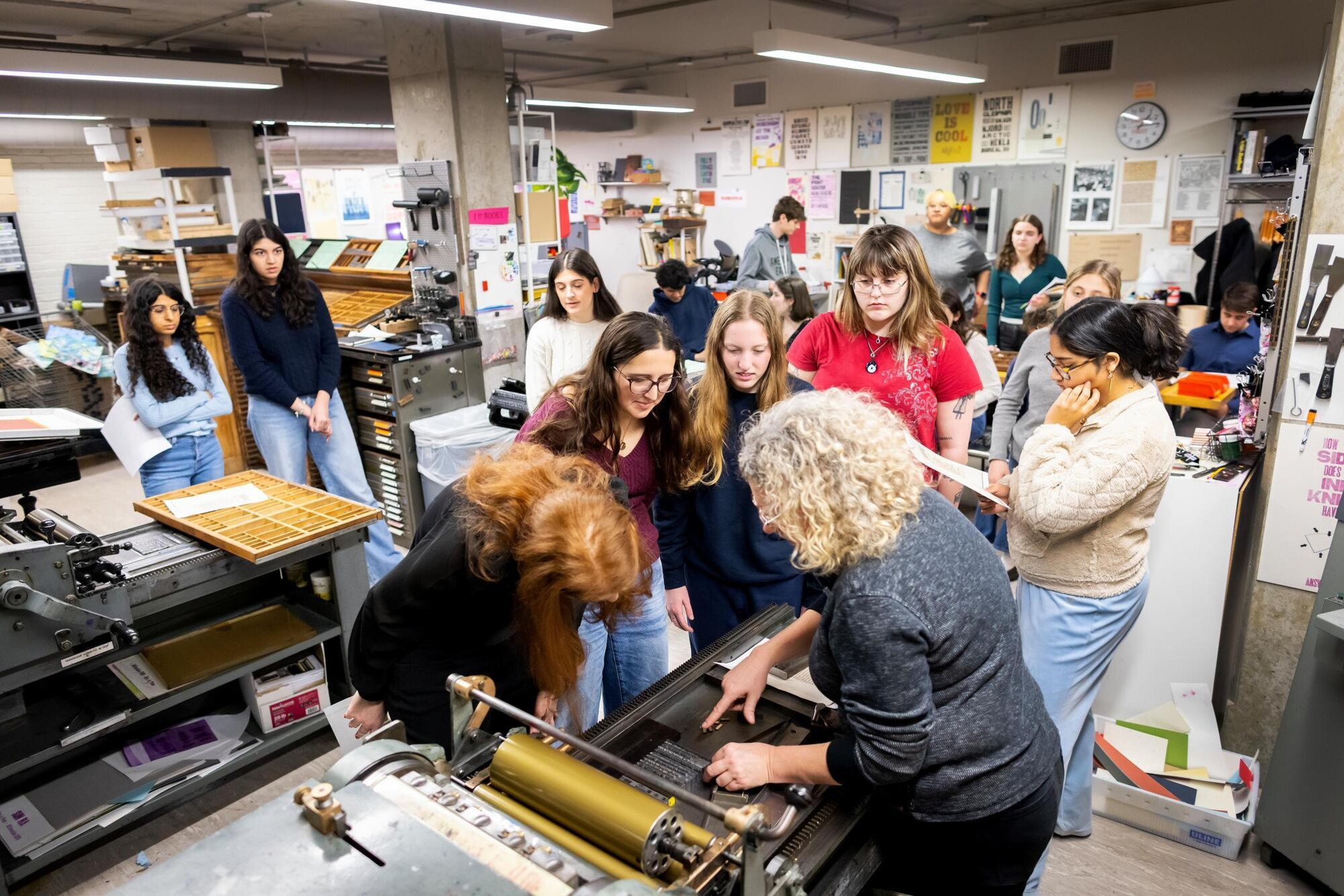 Students watching a demo of a machine in the Common Press office.