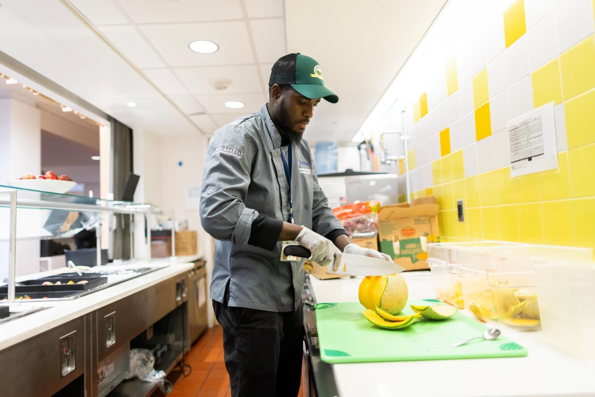 A person slicing melon at Penn Dining.