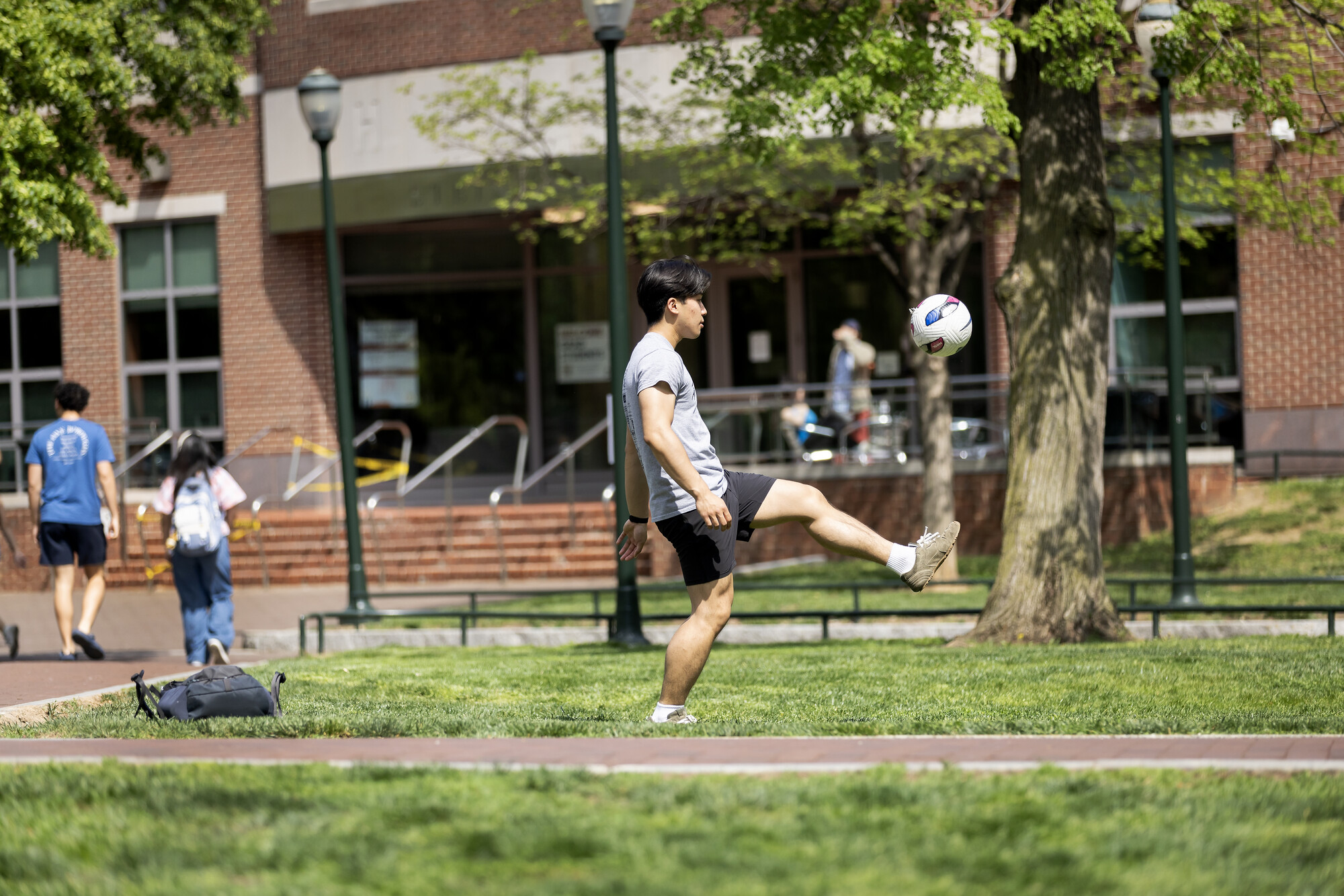 A person kicking a soccer ball on High Rise Field.