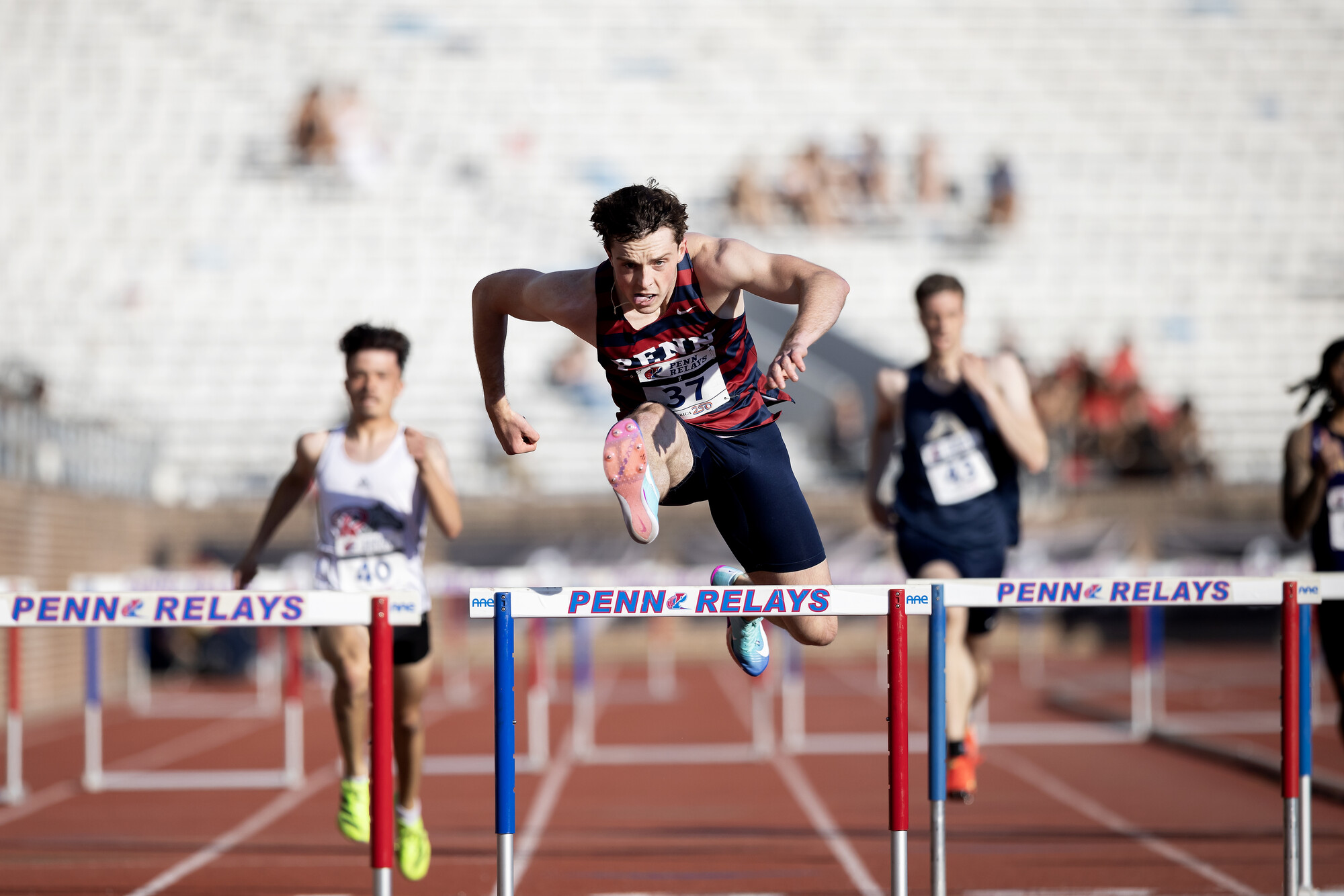 A person jumping over hurdles during Penn Relays