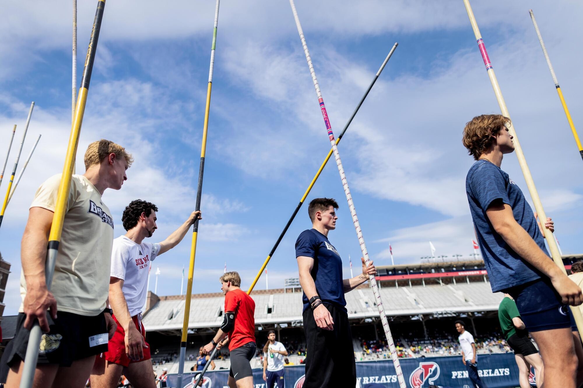 Pole vaulters lining up on Franklin Field with their poles.