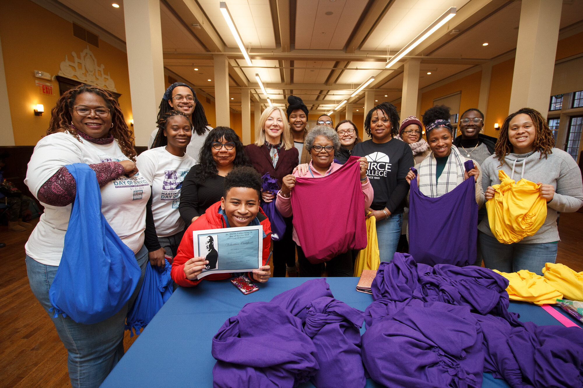 Amy Gutmann standing with community members at a clothing-related volunteer event. The group is smiling and facing forward.