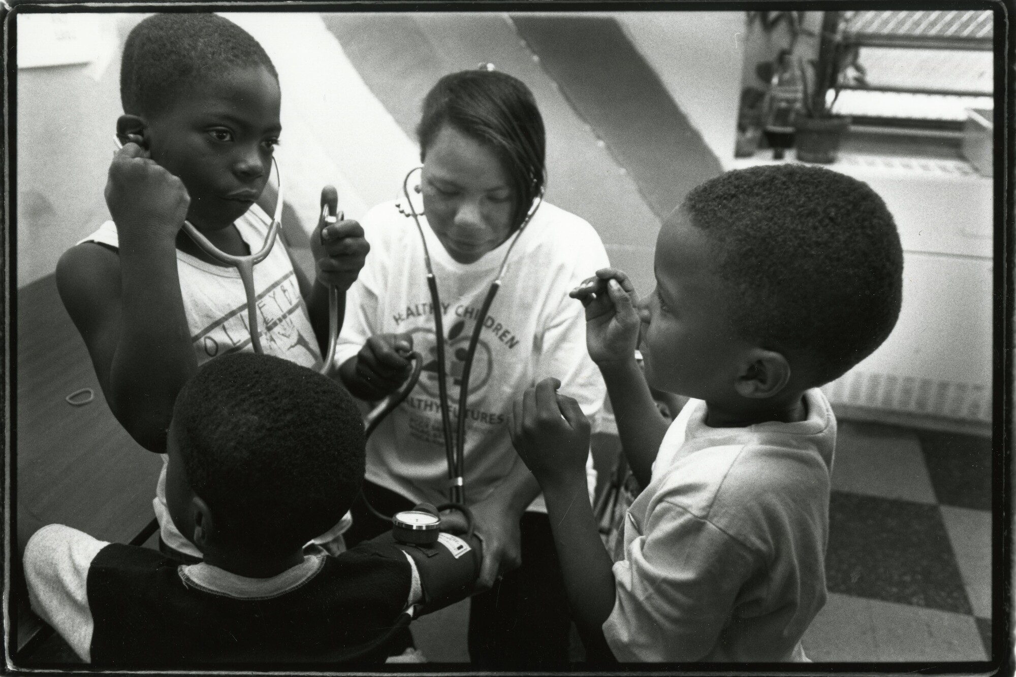 A Penn affiliate (center) sharing a stethoscope with young children in a school/clinic setting.