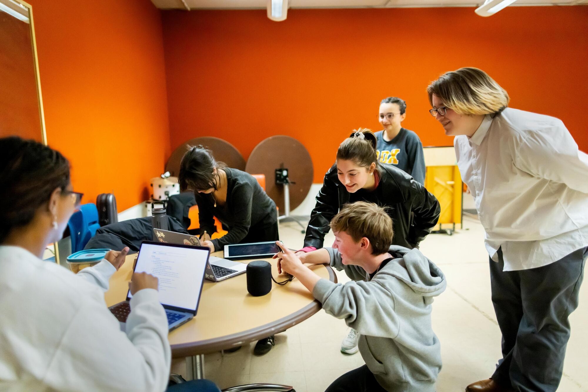 Students in the Quadramics group circled around a table, smiling while looking at a screen and planning their routine.