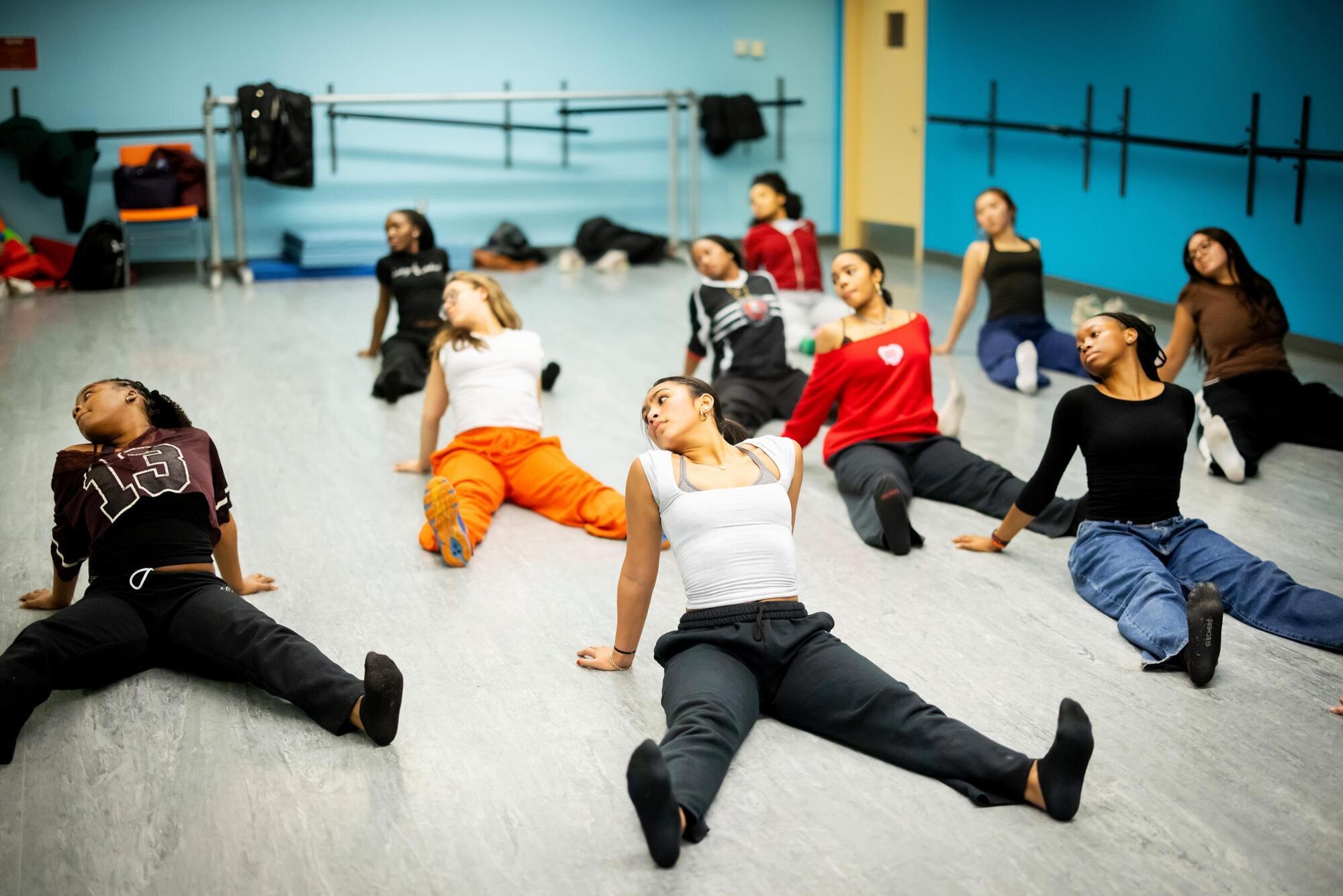 Students in the Strictly Funk group sitting on the floor and striking a pose in unison, all looking in the same direction