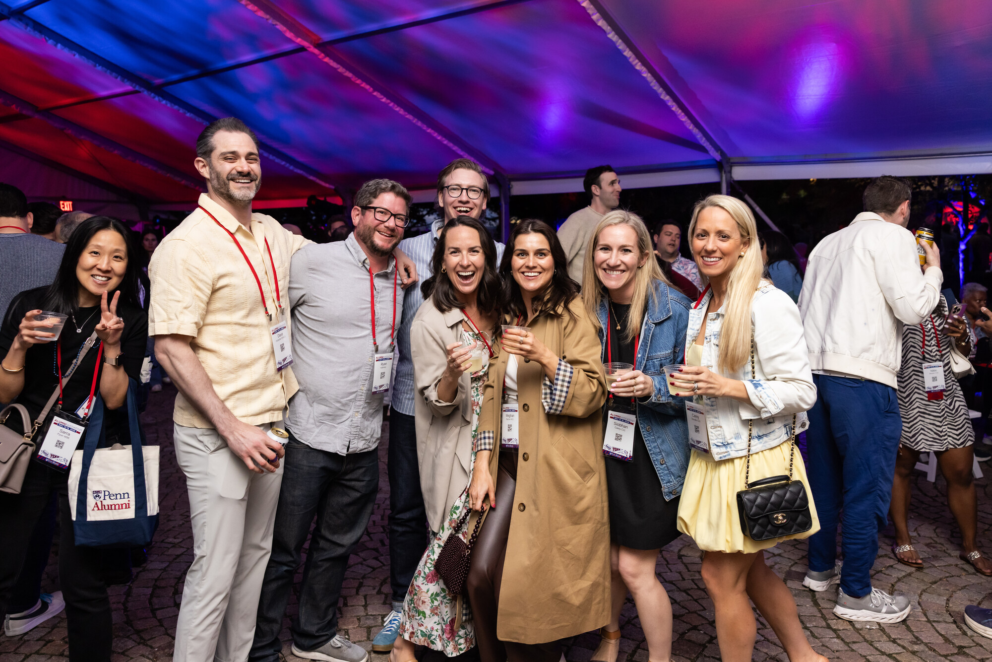 Penn alum posing for a group photo in a tent at night.