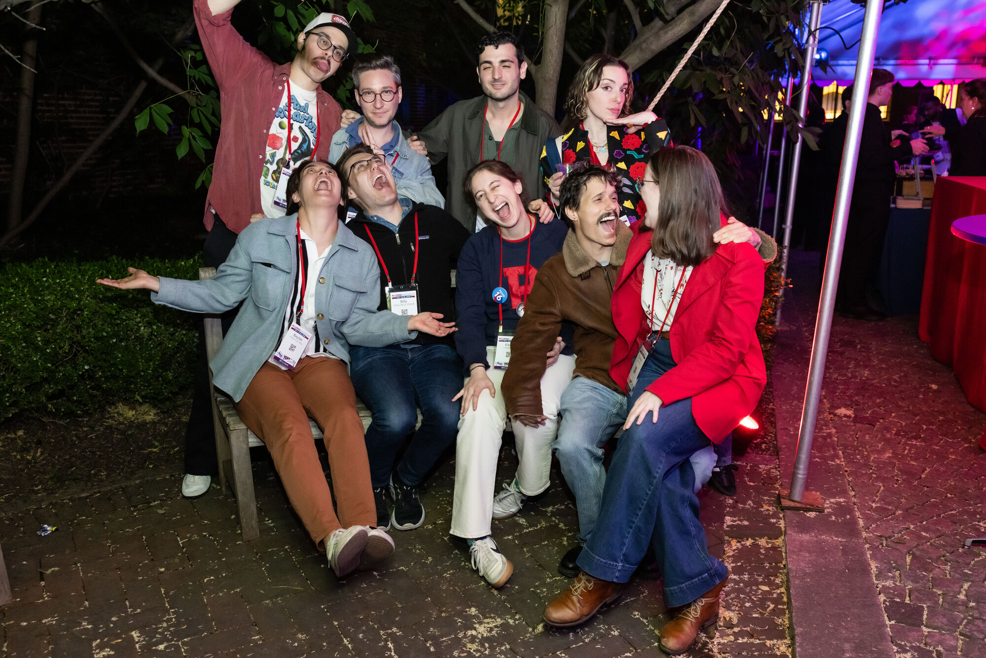 A group of Penn alum posing for a group photo at night.