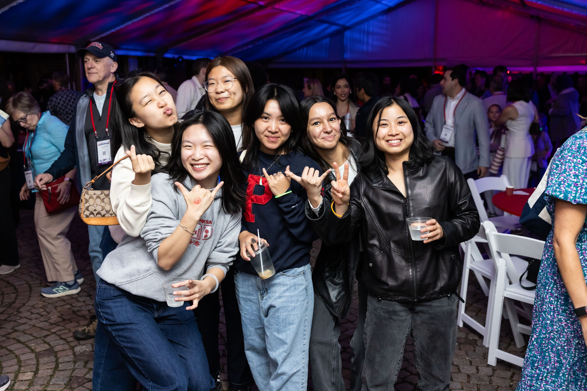 A group of Penn alumni posing for a group photo in a tent at night.