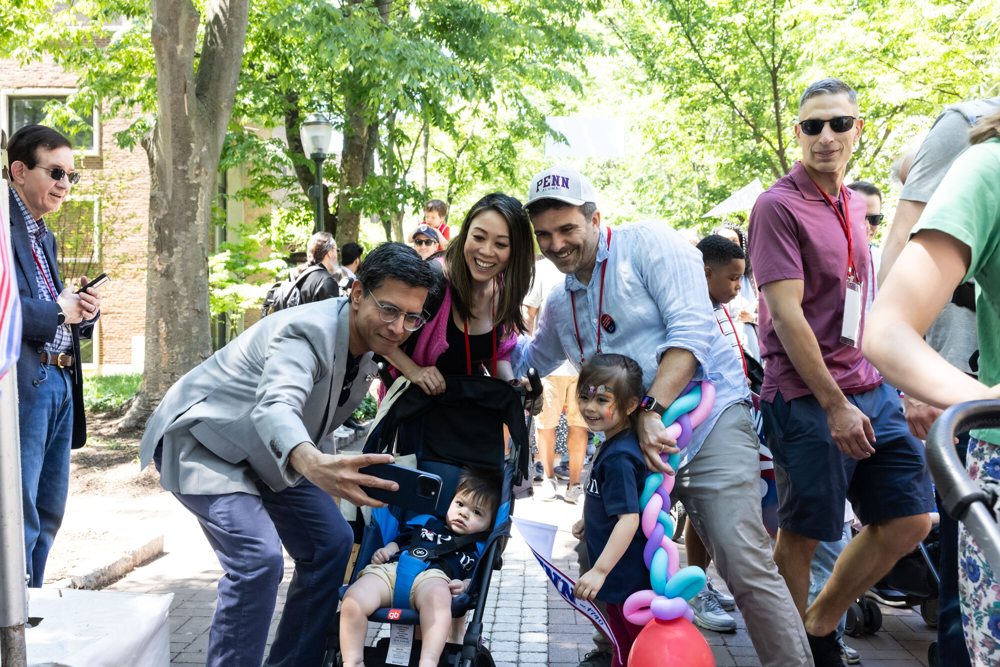 Penn alumni taking a photo with children on Locust Walk.