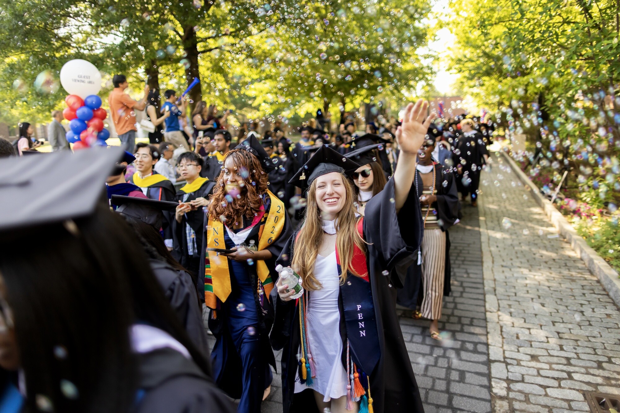 Students walking down Locust Walk in full regalia towards Commencement.