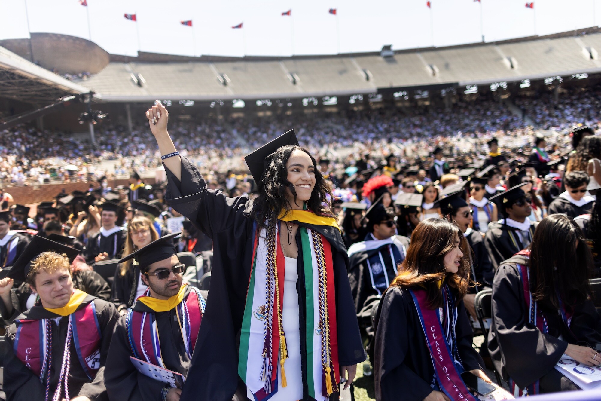 A graduate standing during commencement on Franklin Field.