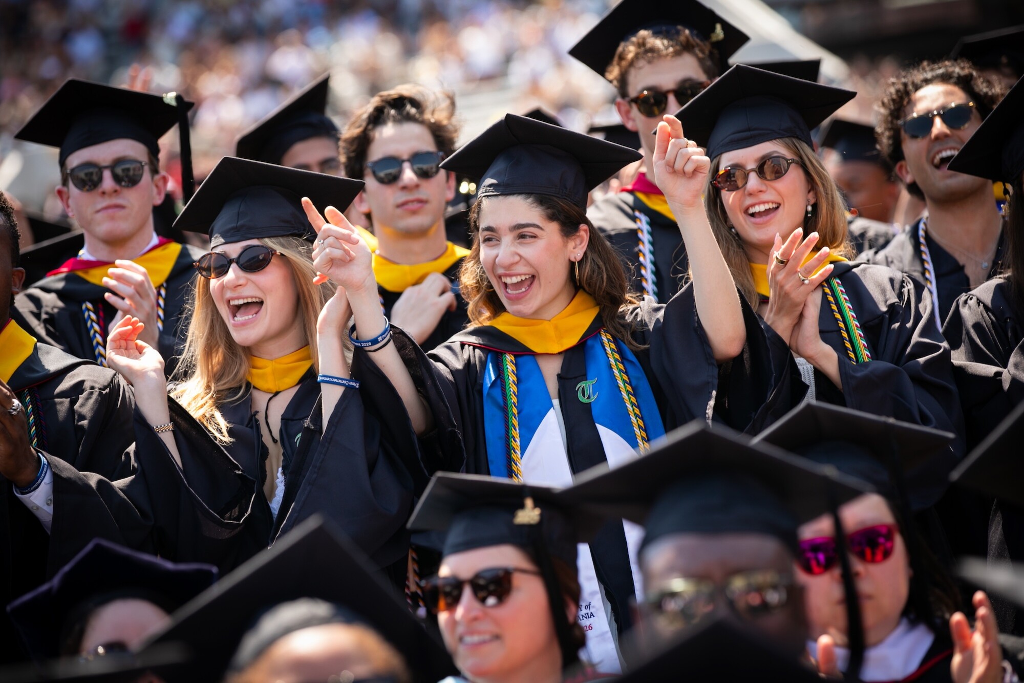 Graduates in regalia celebrating on Franklin Field during commencement.