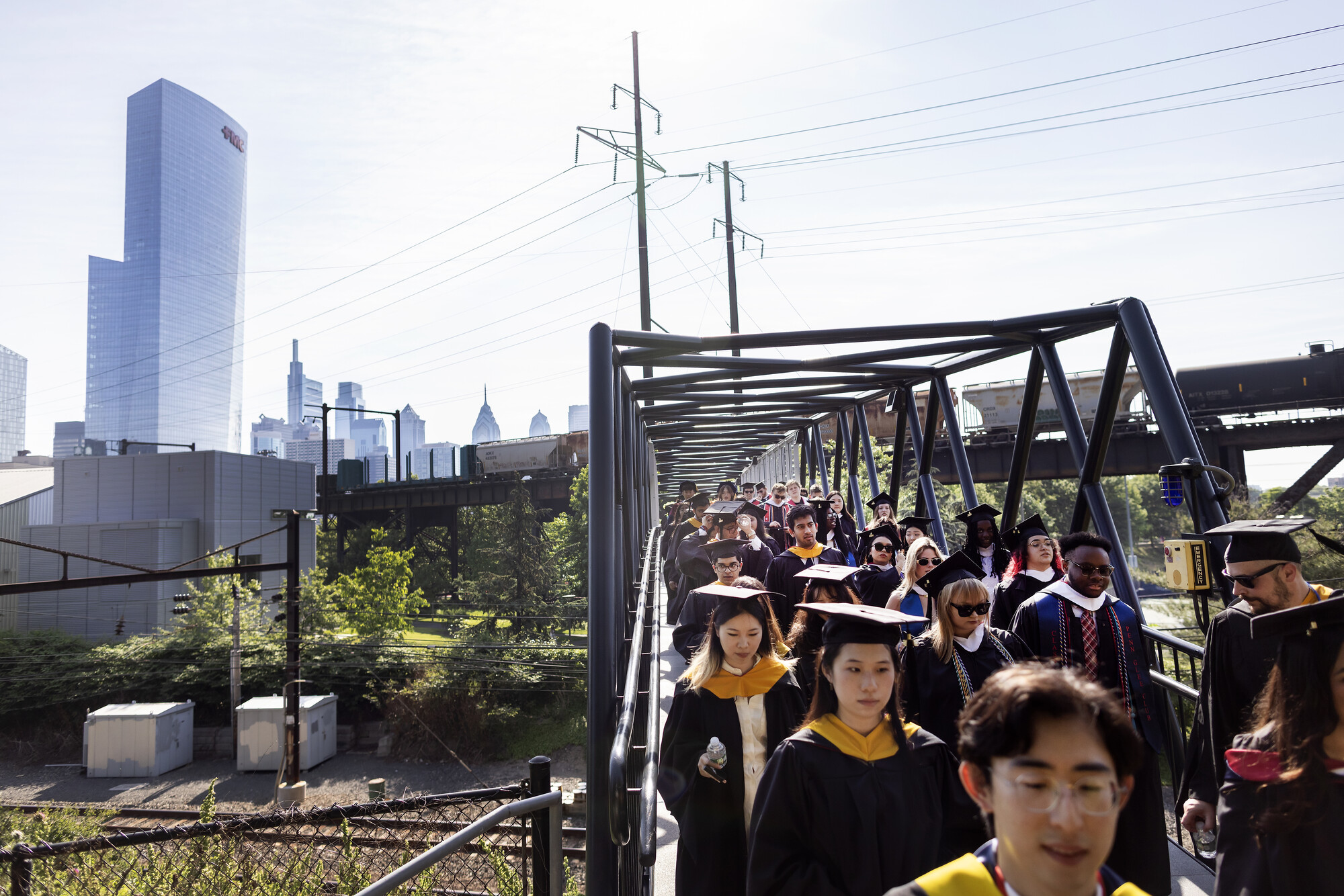 Penn graduates at Comencement walking to Franklin Field in regalia.