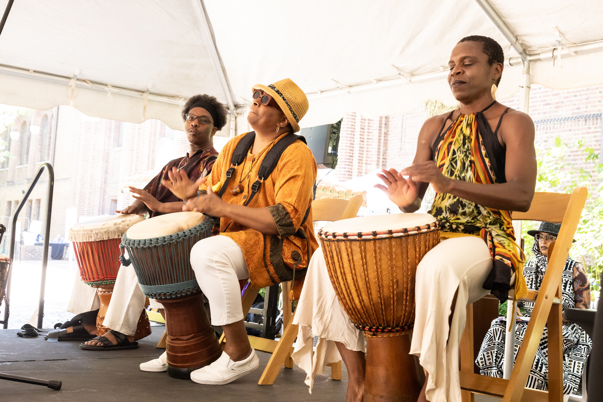 Three people drumming on stage during the Penn Museum Juneteenth performance celebration.