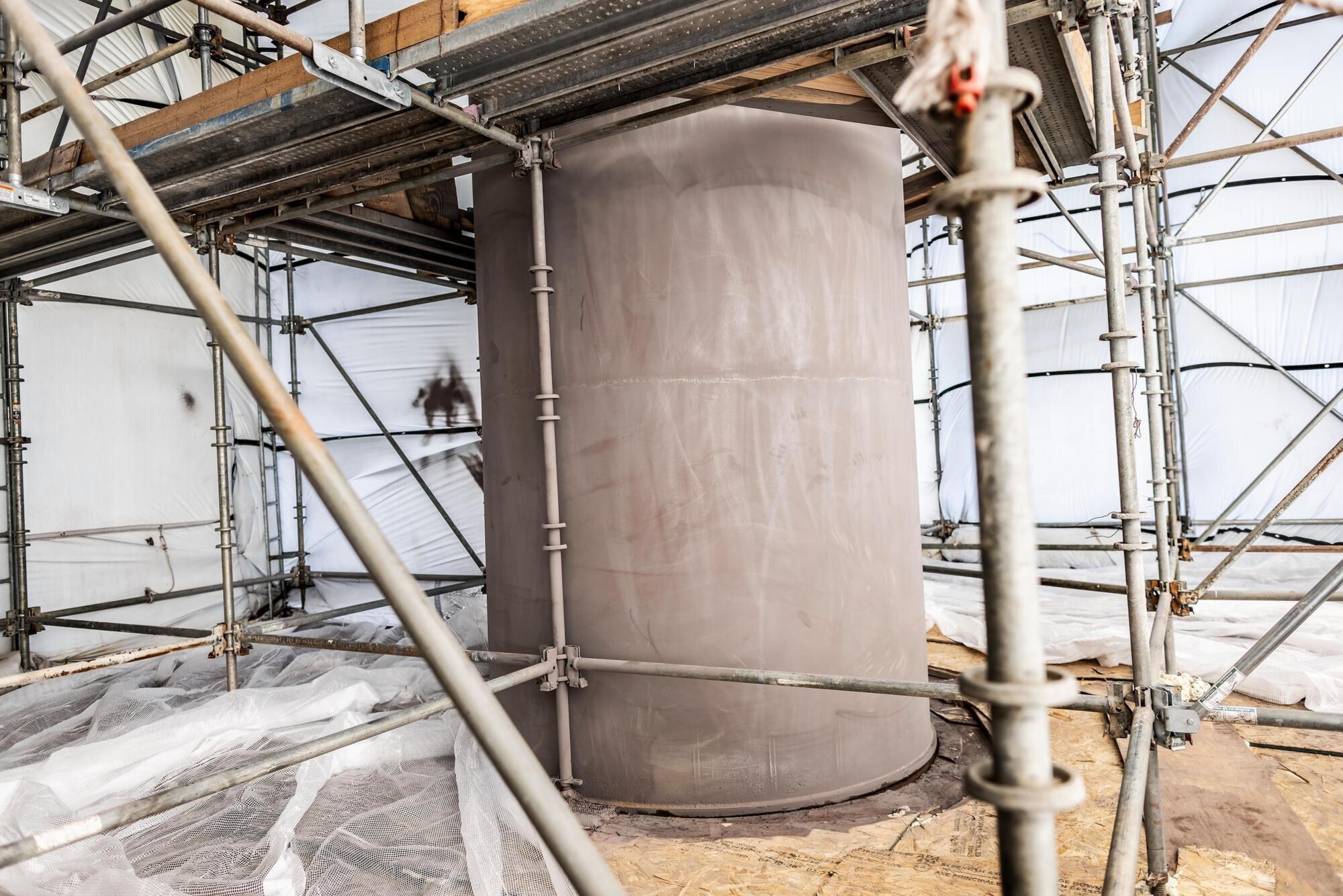 Covenant during the restoration process, stripped of its aged red coat to prepare for a new layer of red paint. The sculpture is surrounded by scaffolding and tenting.