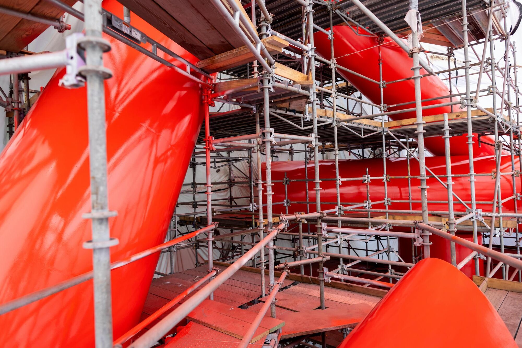 Covenant during the restoration process, newly coated in bright red. The sculpture is surrounded by scaffolding and tenting.