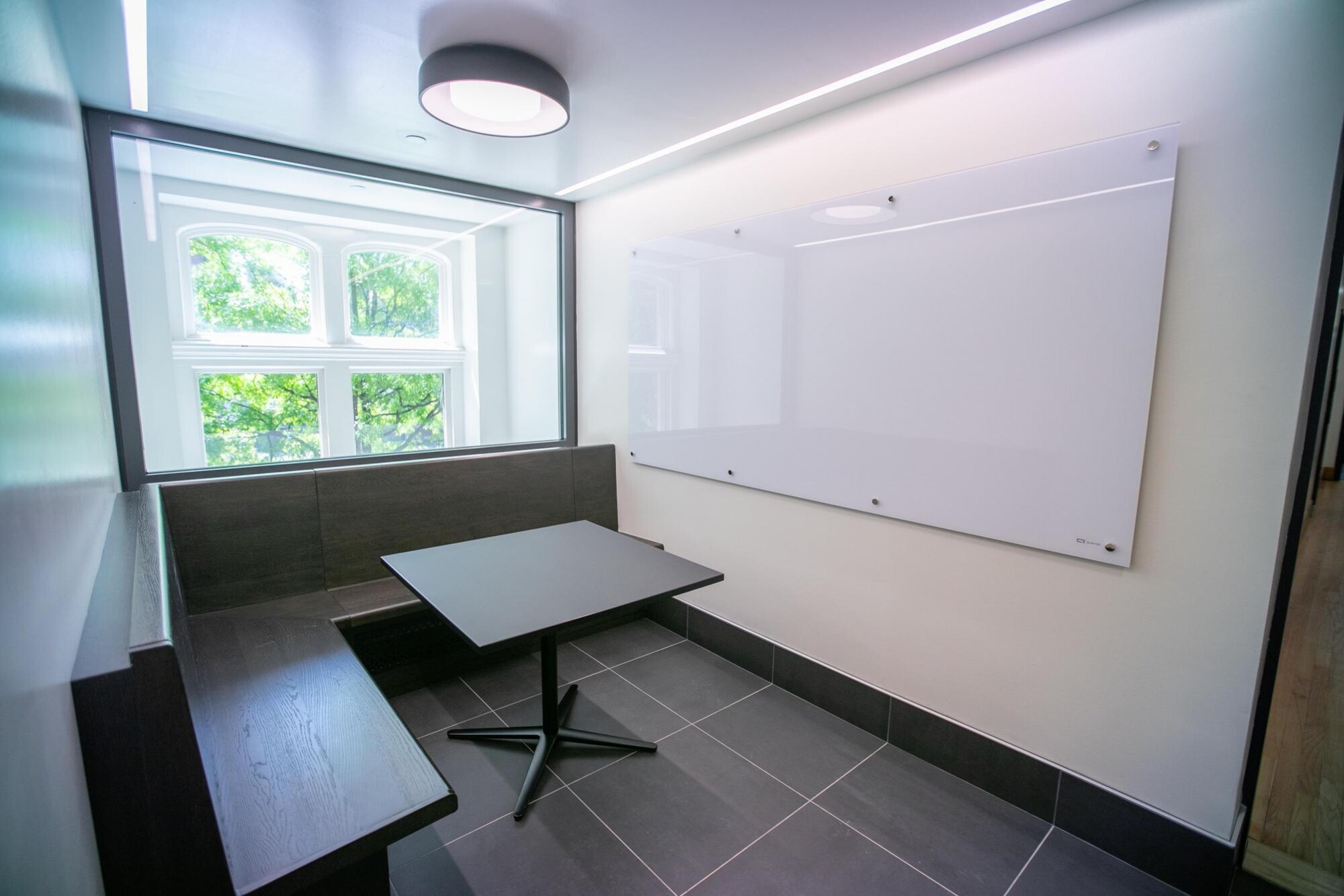 Corner table and white board with a window in the background.