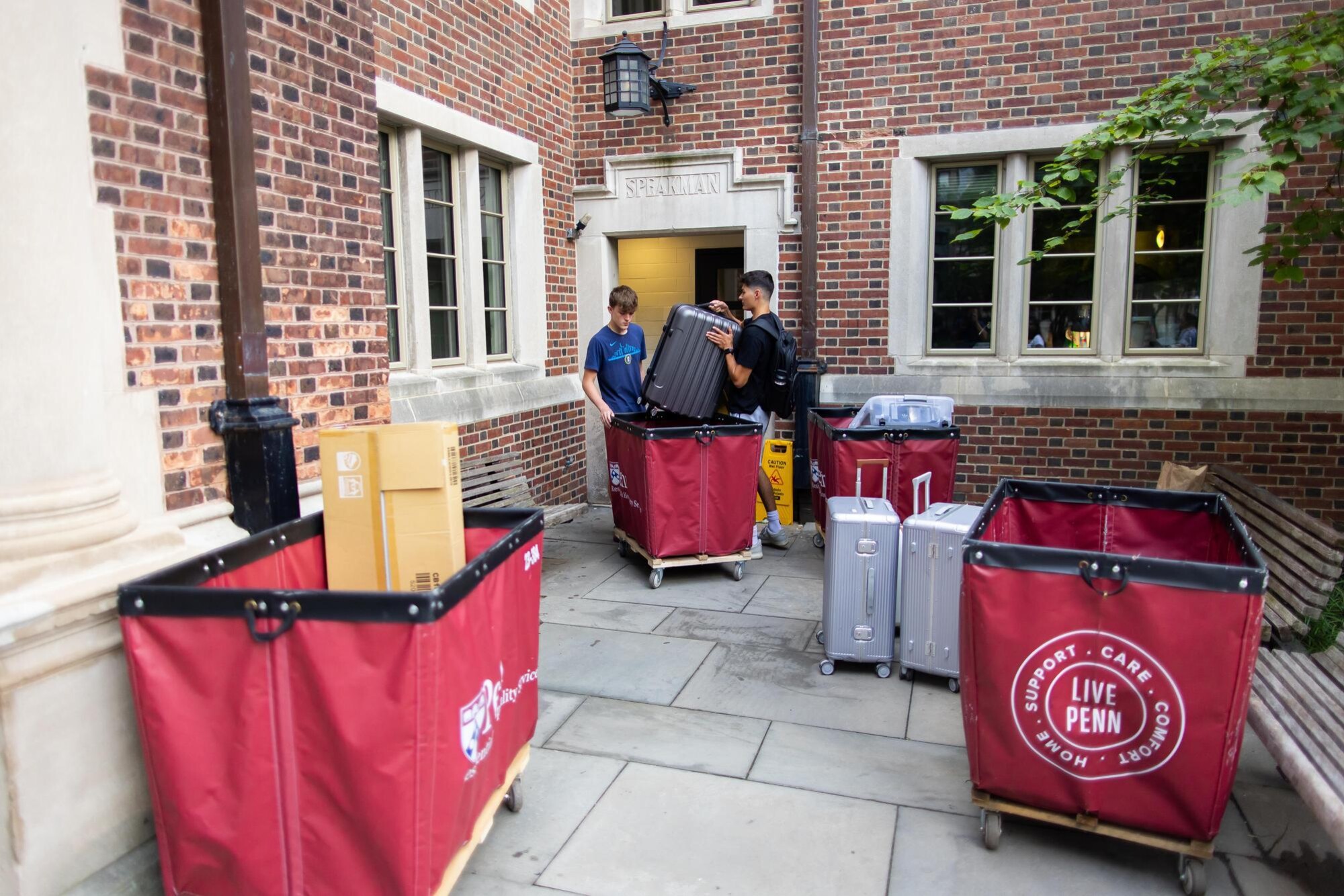 Two students and several move-in carts outside a dorm at the Quad during Move-In.