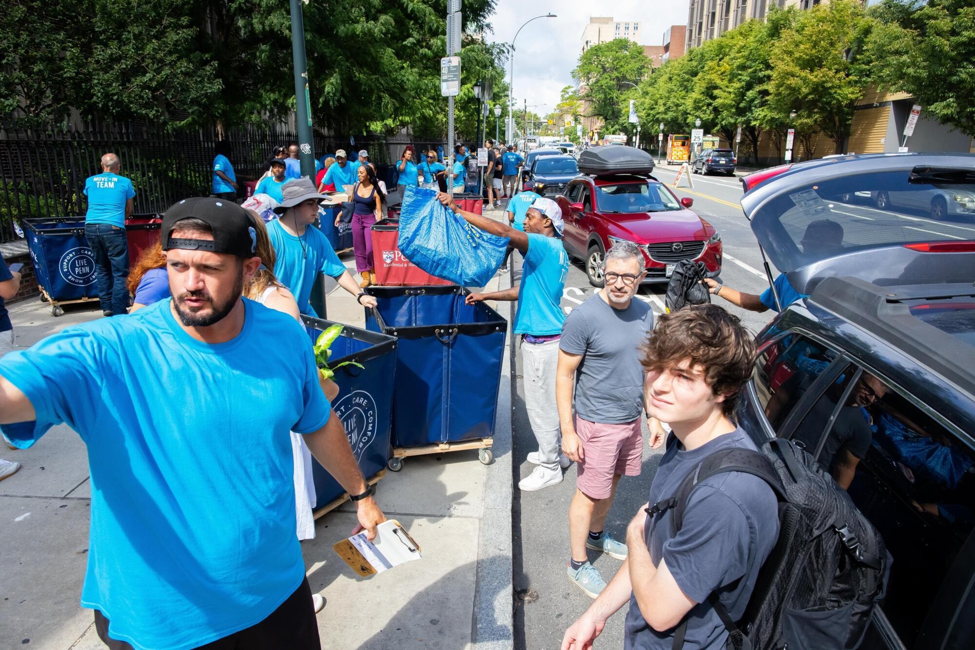 Move-in crew on the sidewalk on Spruce Street unloading parked cars during Move-In.