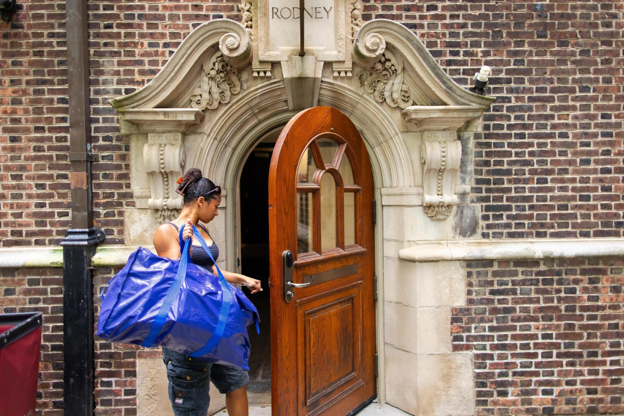 A student walking into the Rodney dorm at the Quad during Move-In.