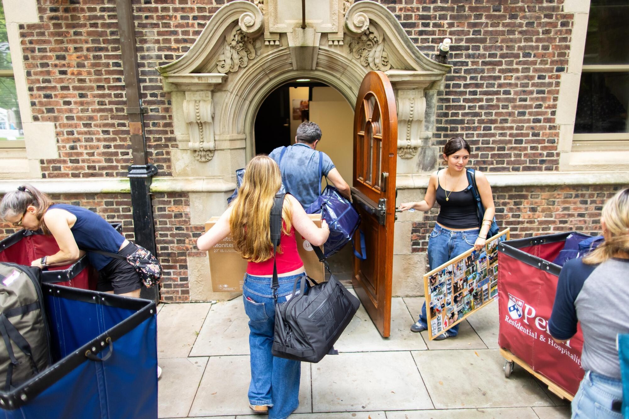Students and parents bringing bags into a dorm in the Quad.