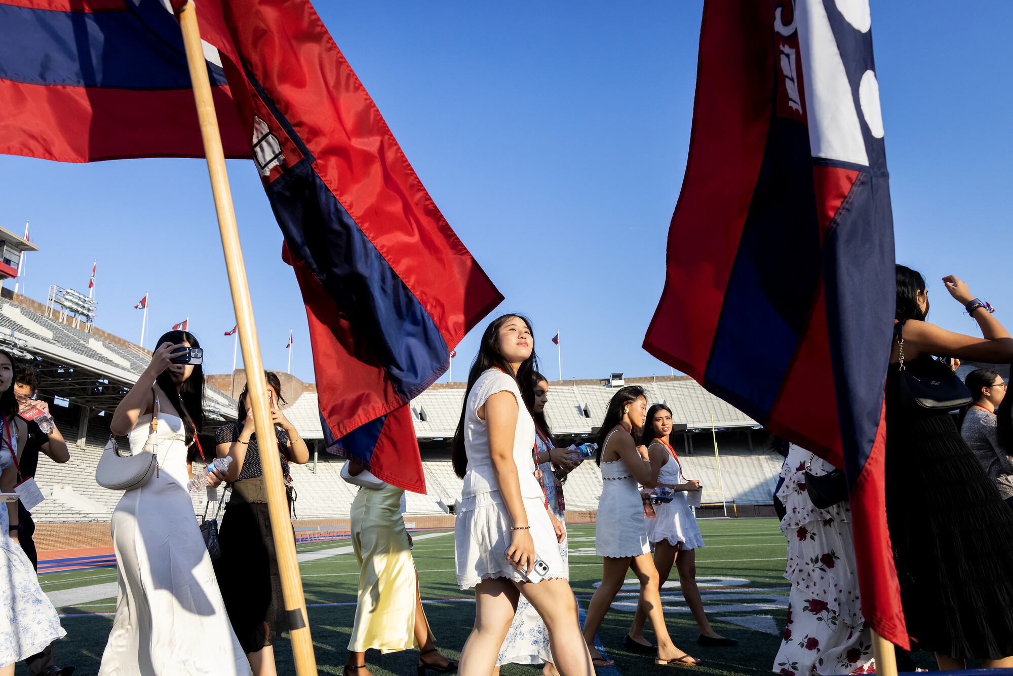 Class of 2030 students walking past flags onto Franklin Field.